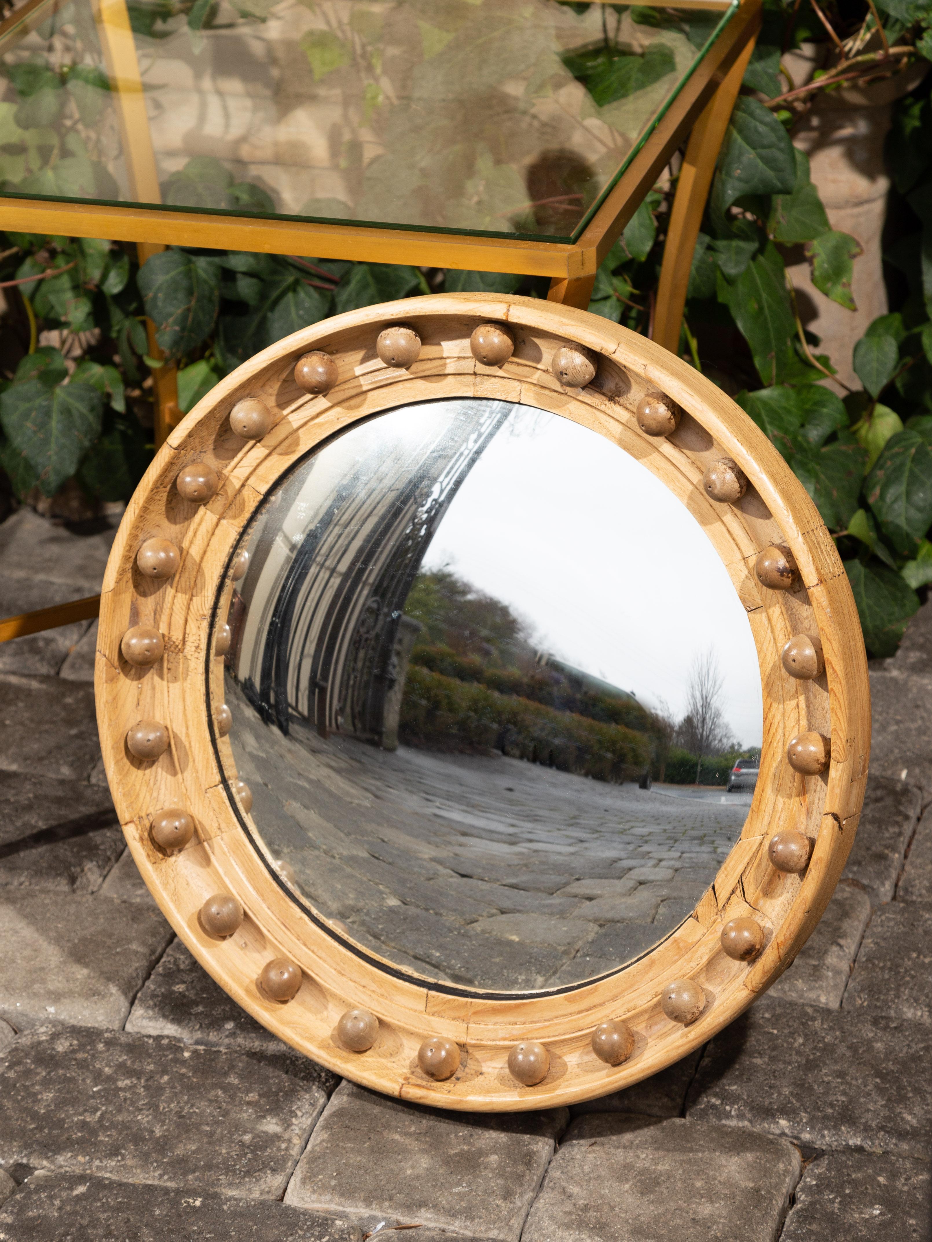 An English oak girandole bullseye convex mirror from the late 19th century with petite spheres and natural finish. Born in England during the last quarter of the 19th century, this bullseye mirror features a convex plate reflecting and distorting