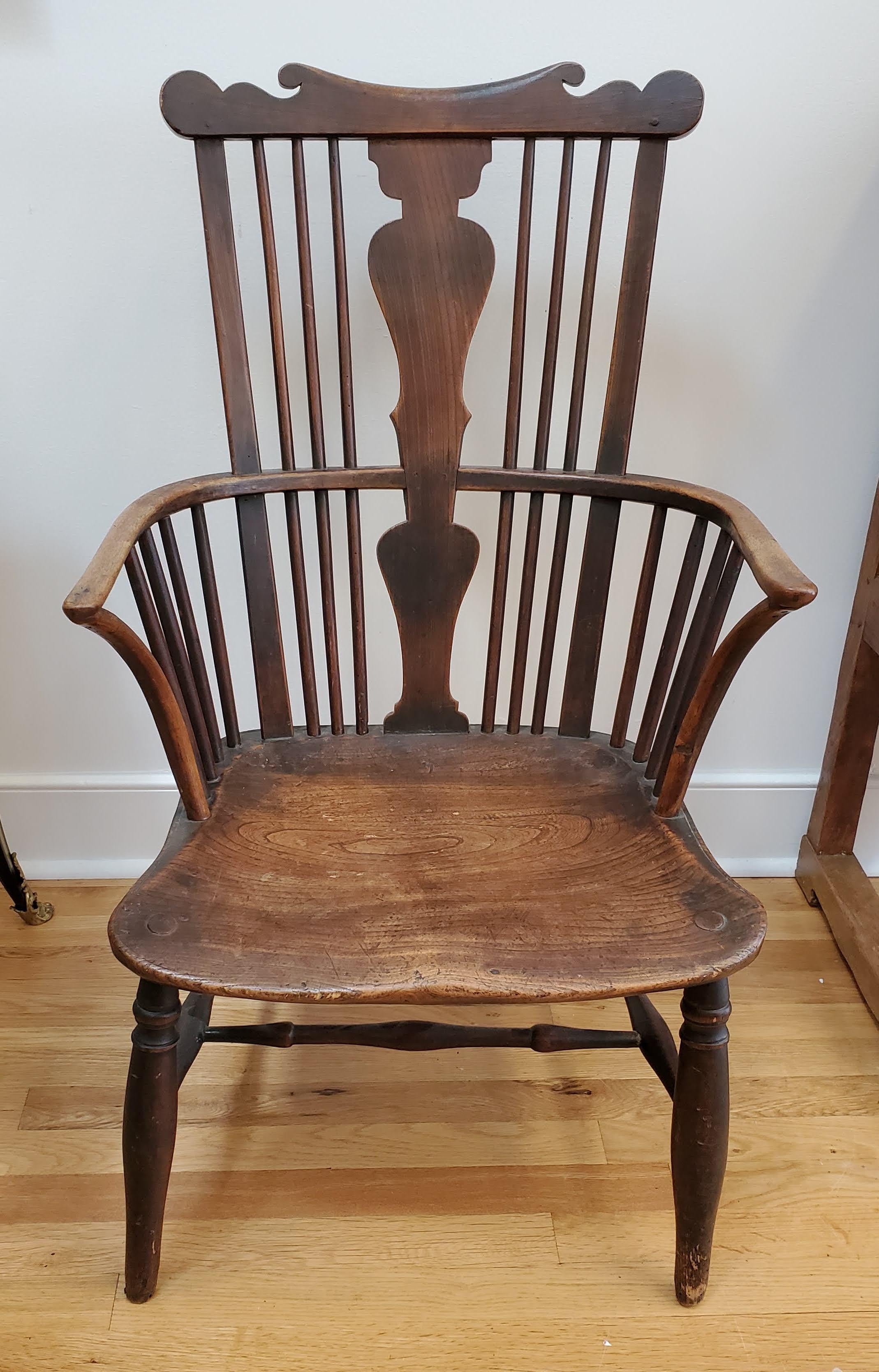 fauteuil Windsor à dossier peigne du 18e siècle. La traverse supérieure en forme de peigne est surmontée d'une douille centrale et d'accoudoirs arqués. L'assise en orme figuré est façonnée et les pieds sont délicatement tournés. Un mélange d'orme,