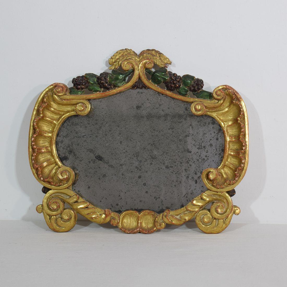 Beautiful carved giltwood Baroque mirror, with its original foxed mirror glass.
Italy, circa 1750. Weathered and minor losses.