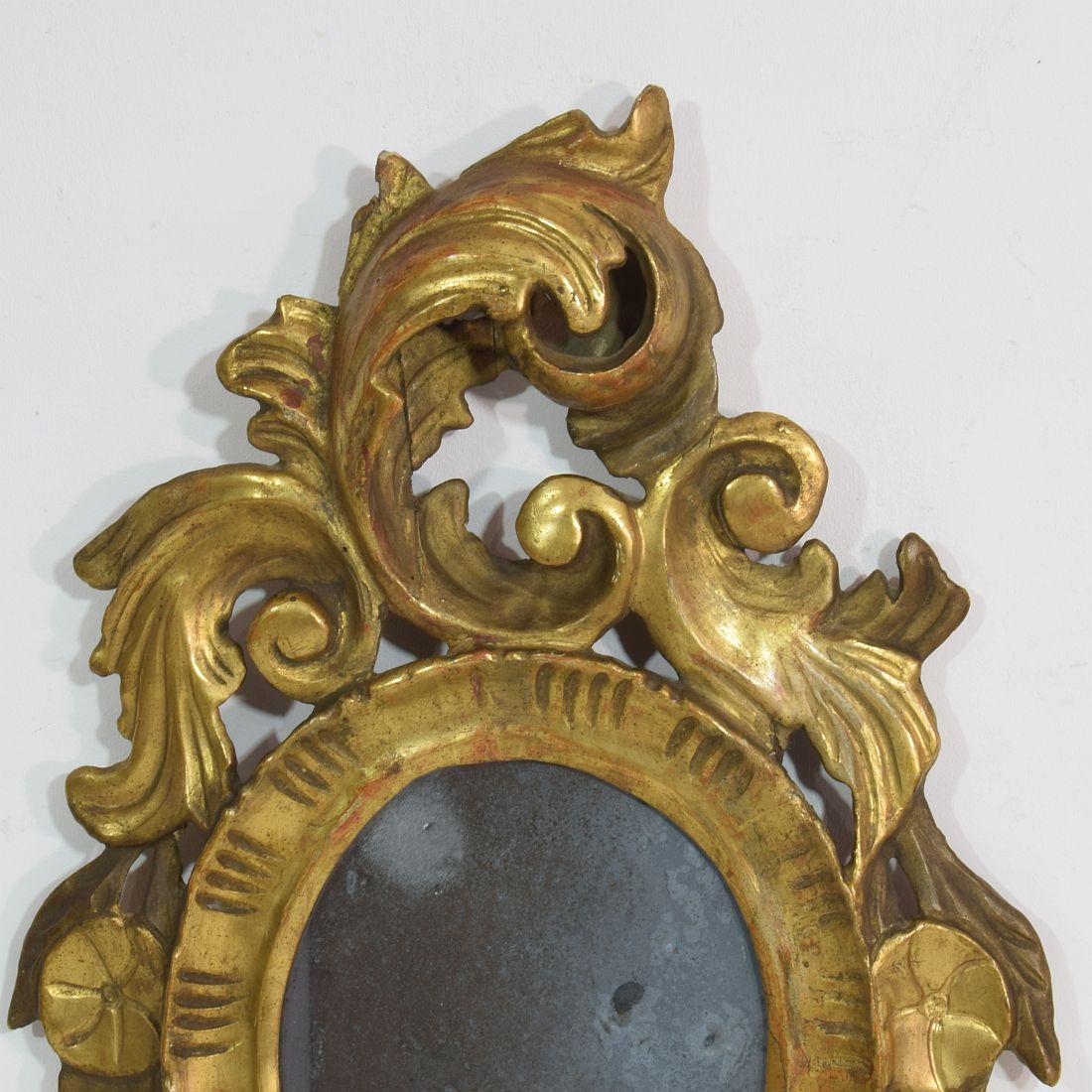 Stunning small Baroque giltwood mirror with beautiful foxed mirror glass. 
Italy circa 1750. Weathered, small losses and old repairs.

  
