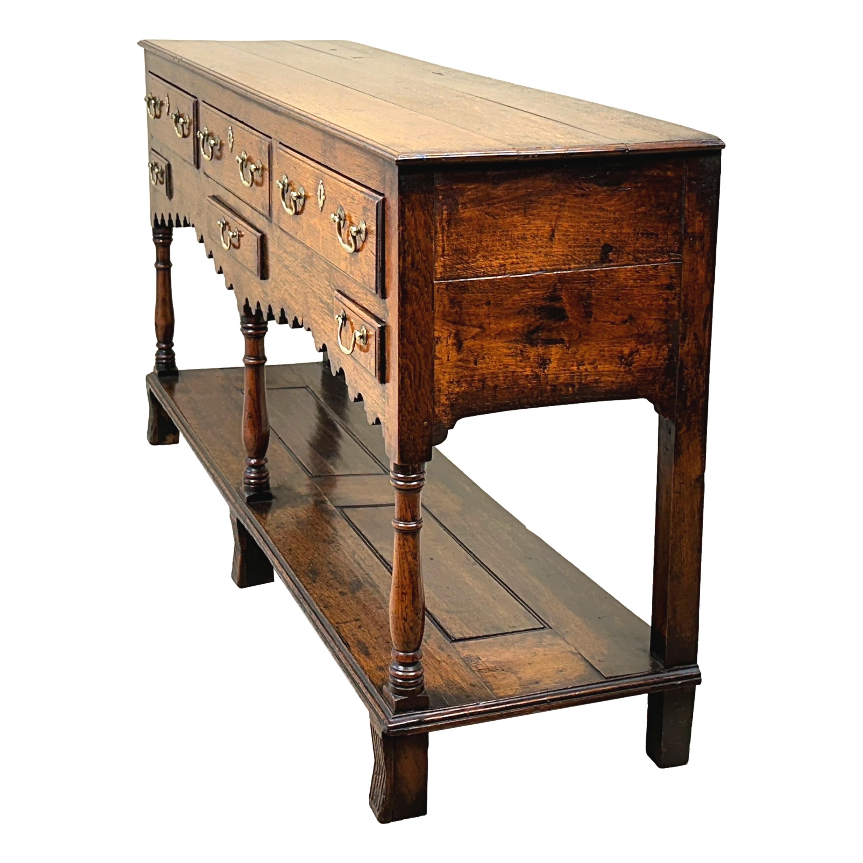 A Charming 18th Century, Georgian, Oak Dresser Base Sideboard Of Attractive Small Proportions, Having Rectangular Plank Top Over Six Drawers Retaining Original Brass Swan Neck Handles And Elegant Shaped Frieze, Raised On Baluster Turned Upright