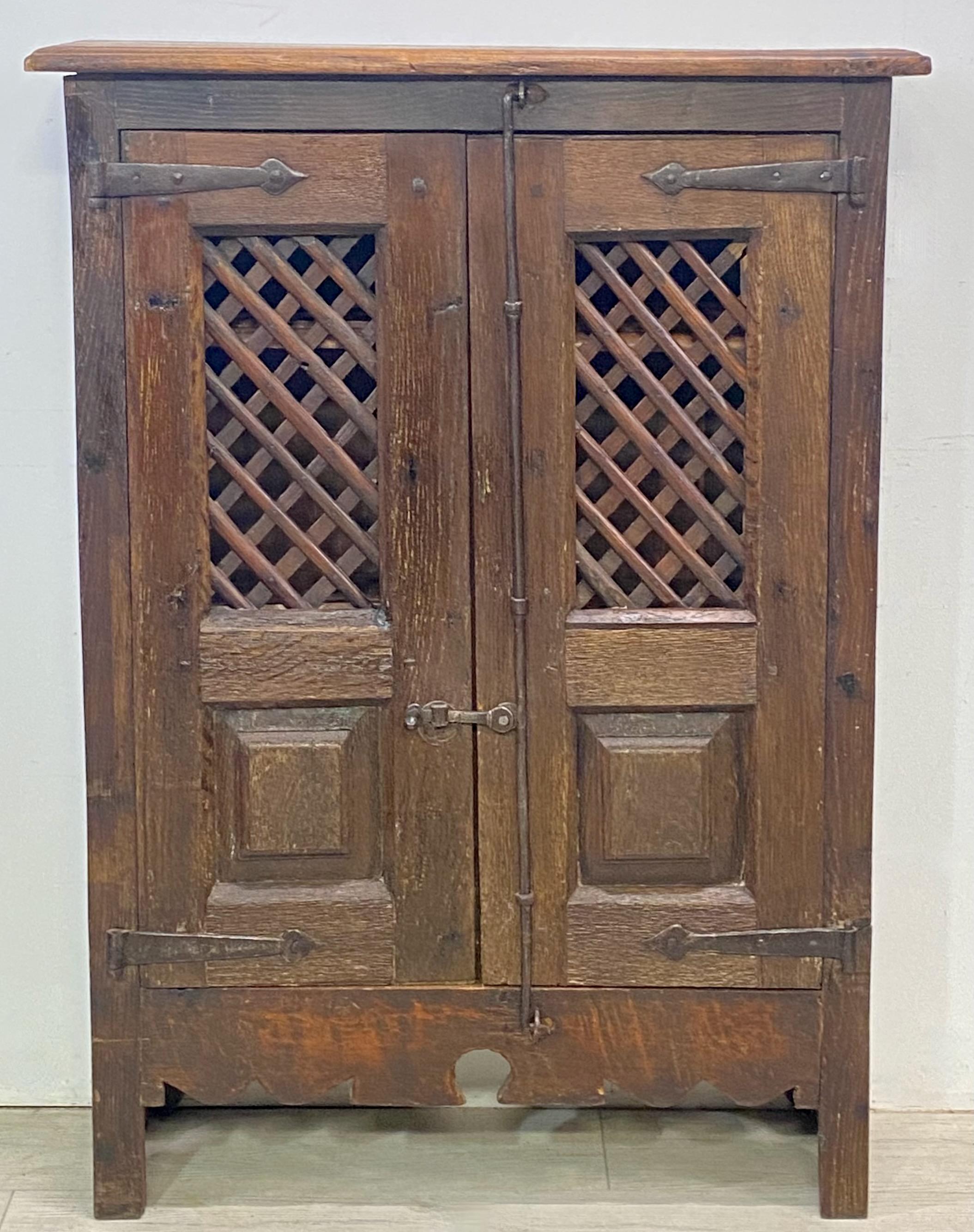An unusually small Spanish Colonial style cabinet that most likely was used for food storage. 
Original hand forged iron hardware, and having mostly its original finish (the top looks to have been cleaned at some point in more recent time). 
18th