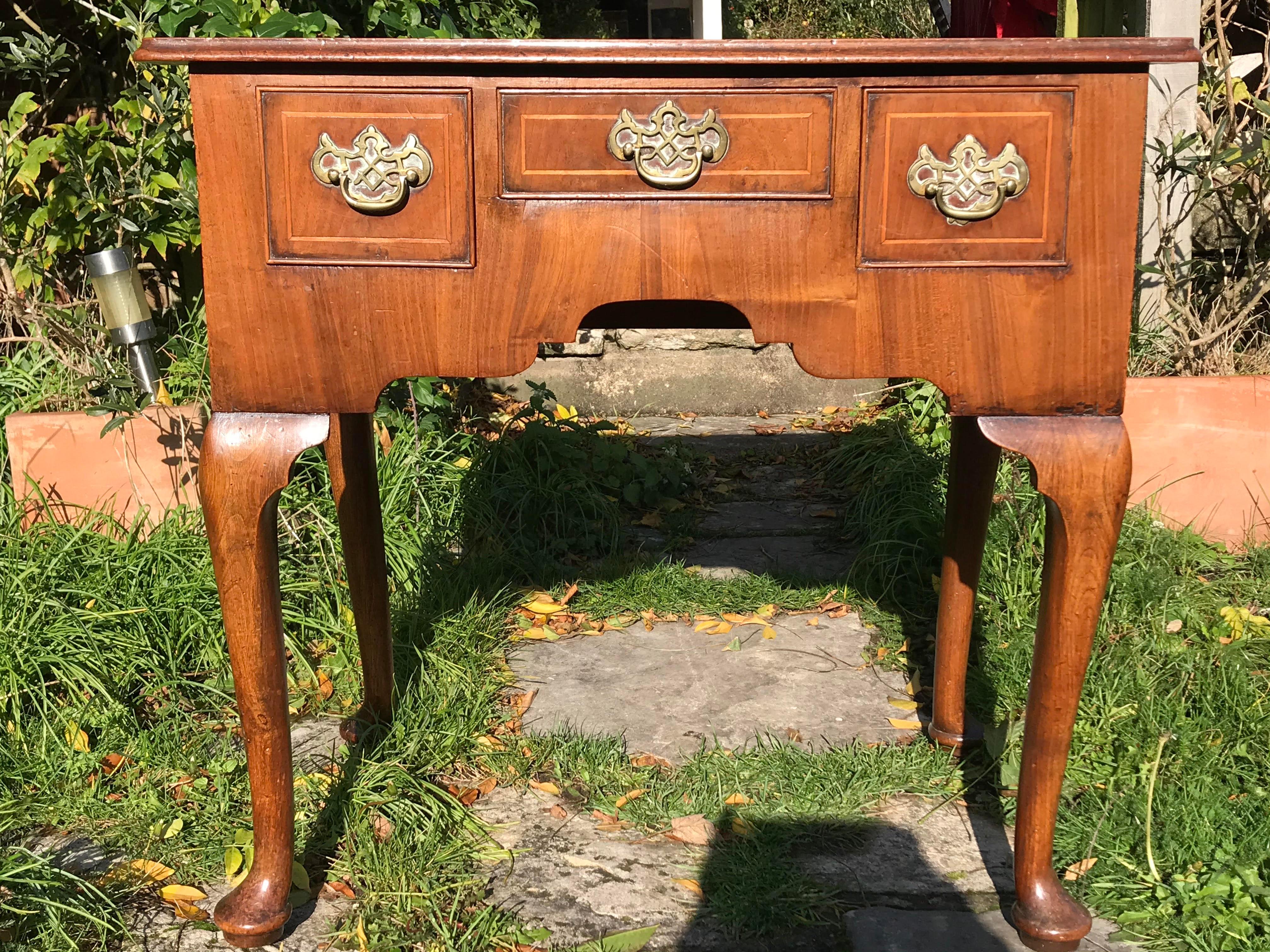 A compact-sized 18th-century walnut lowboy / dressing table / vanity.
George II period, circa 1750.

Raised on cabriole legs, this small English walnut table is only 2' 5'' wide.
Retaining its original open-fret brasses, which are typical of the