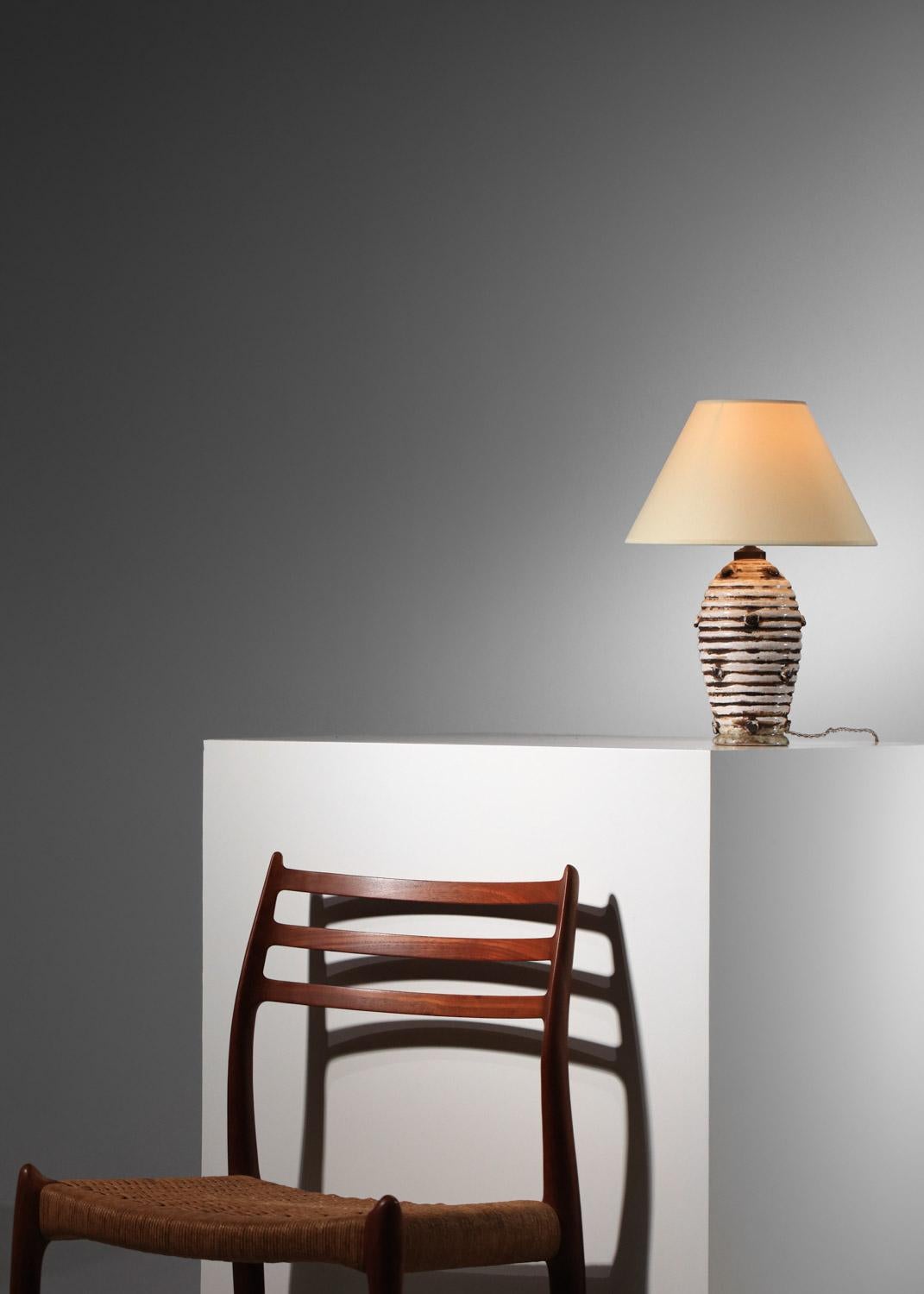 Lámpara de sobremesa francesa de los años 30 del estilo de Jean Besnard. Base de cerámica esmaltada en tonos blancos y marrones, decorada con cabujones de cerámica. Una lámpara muy original y decorativa. Sistema eléctrico renovado con enchufe
