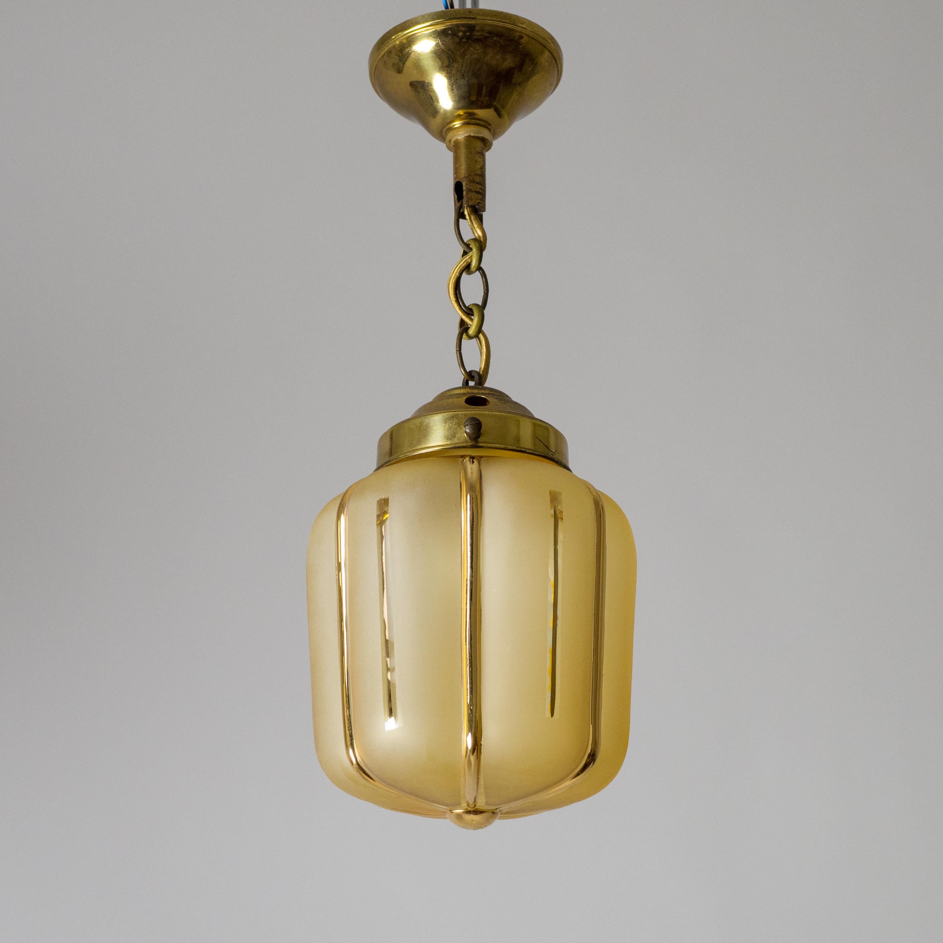 Charming petite French Art Deco pendant from the 1940s. Brass hardware with an amber glass diffuser with a satin finish and gold-paint details. Very fine original condition with some patina on the brass. One brass and ceramic E14 socket with new