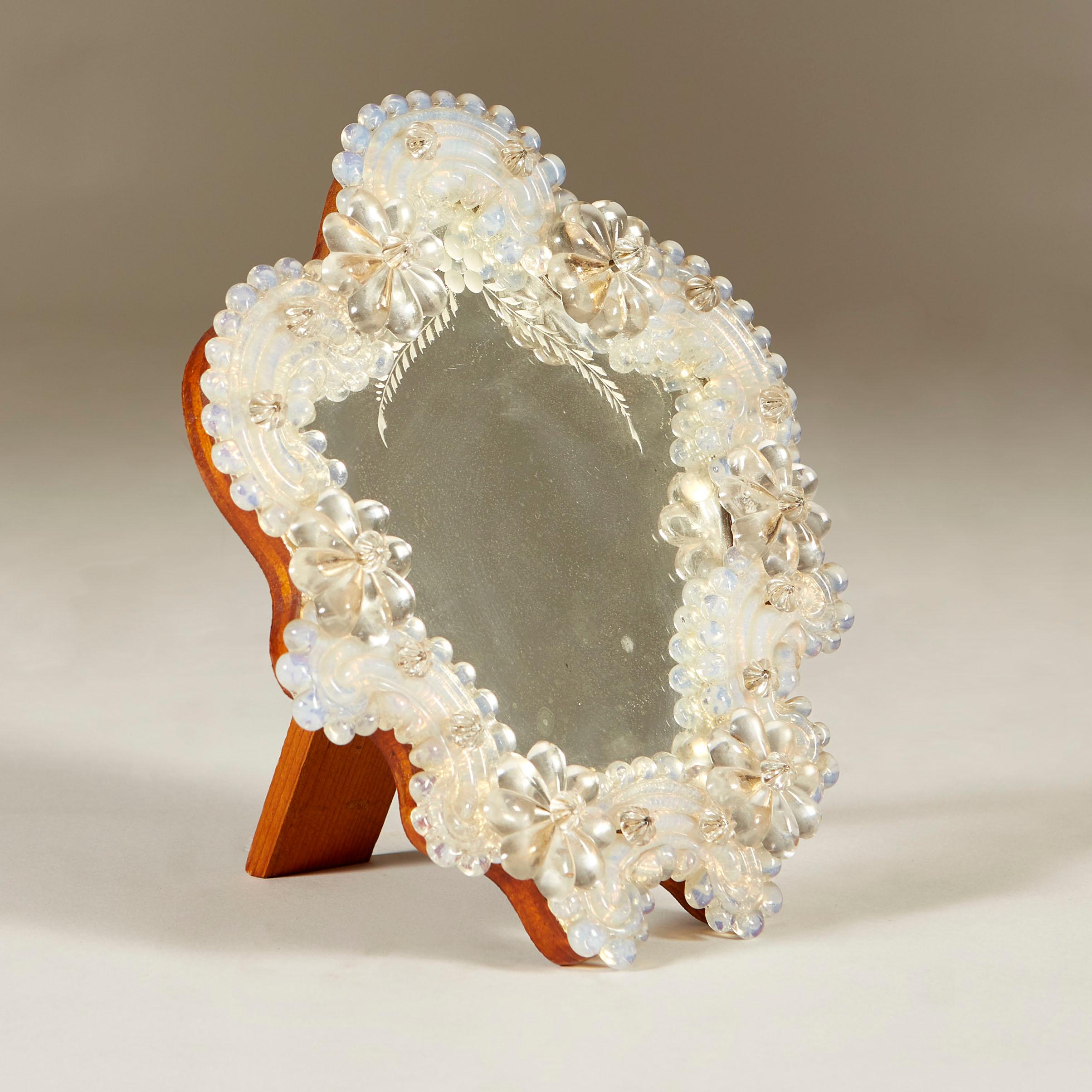 Highly decorative small Venetian flower mirror which can either hang on a wall or sit on a table. Six clear glass flowers interspersed with ribbed opaque glass pieces. Original mirror etched with flower and laurels. Sits on wooded back and strut but