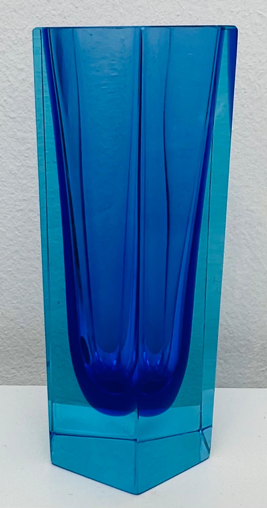 A very unusual and Murano blue and turquoise glass vase. The original round foil sticker is visible on one side marked: Murano Made In Italy. A beautiful decorative piece perfect for a glass display case or shelf where the light can shine through it