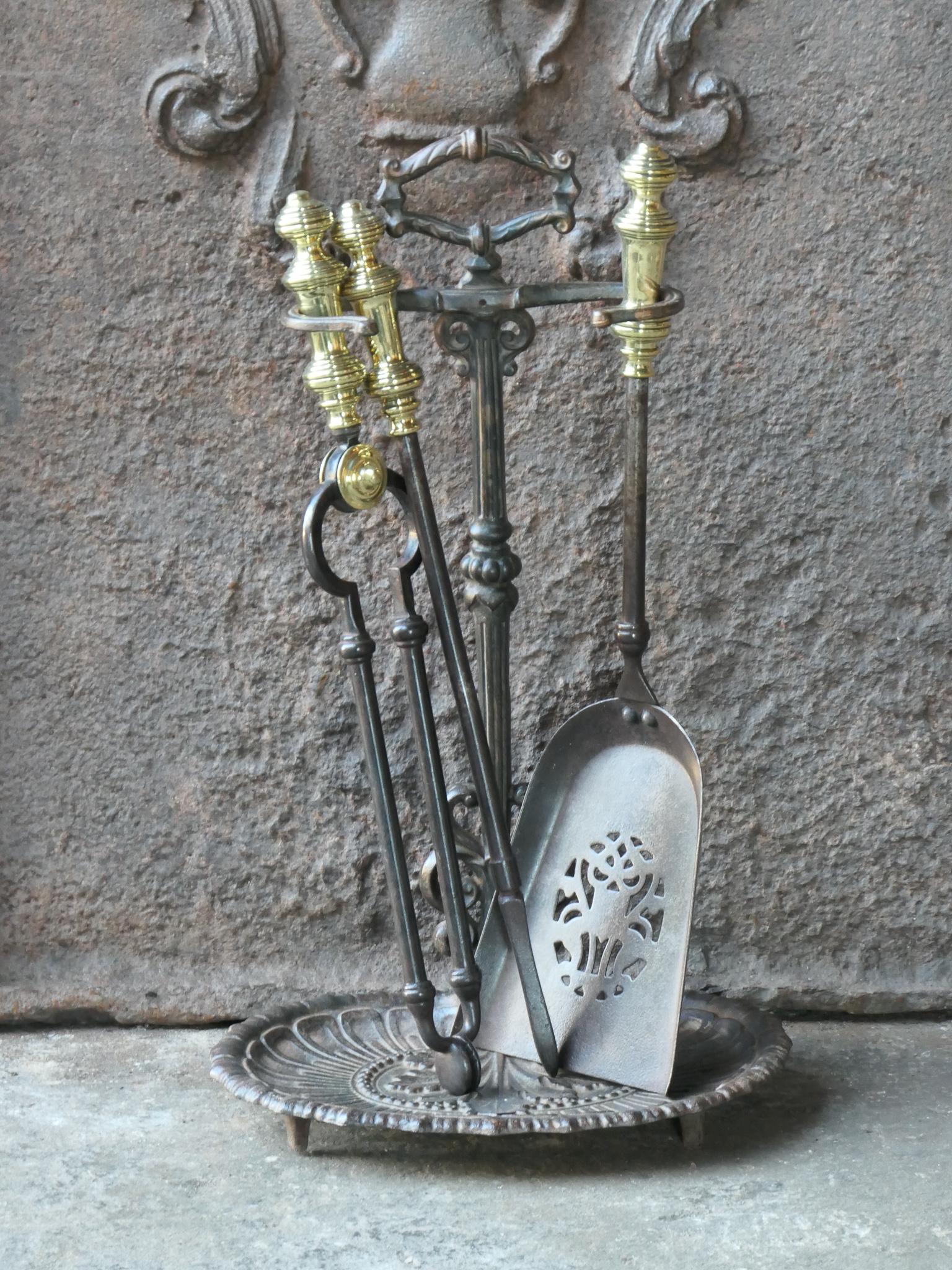 Beautiful small 19th century English Victorian fireplace tool set. The tool set consists of tongs, shovel, poker and stand. The stand is made of wrought iron with a cast iron base, and the tools are made of wrought iron with polished brass