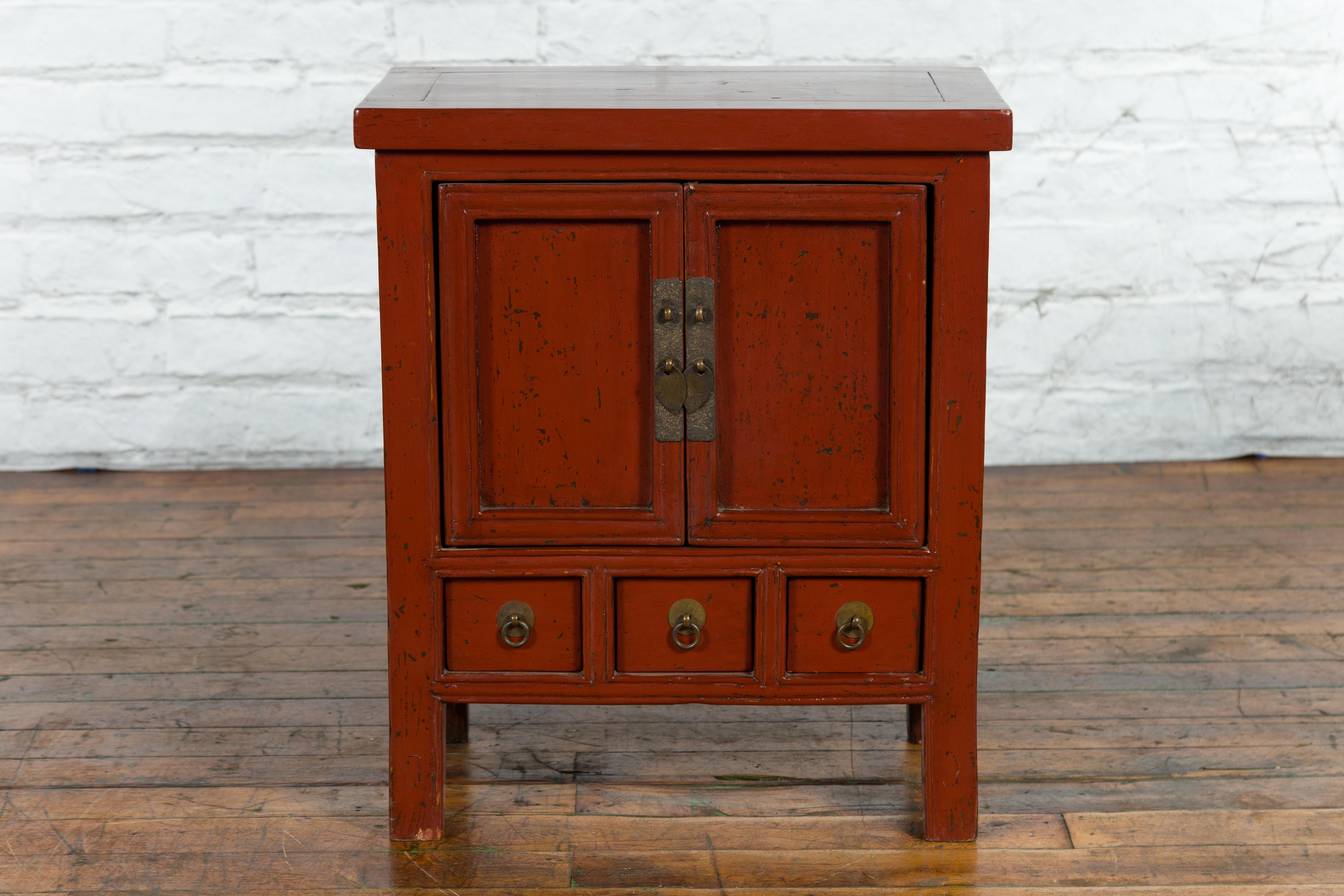 A Chinese Qing Dynasty period small red lacquered side cabinet from the 19th century, with three apothecary drawers. Created in China during the Qing Dynasty, this small red lacquer cabinet features a rectangular top with central board, sitting
