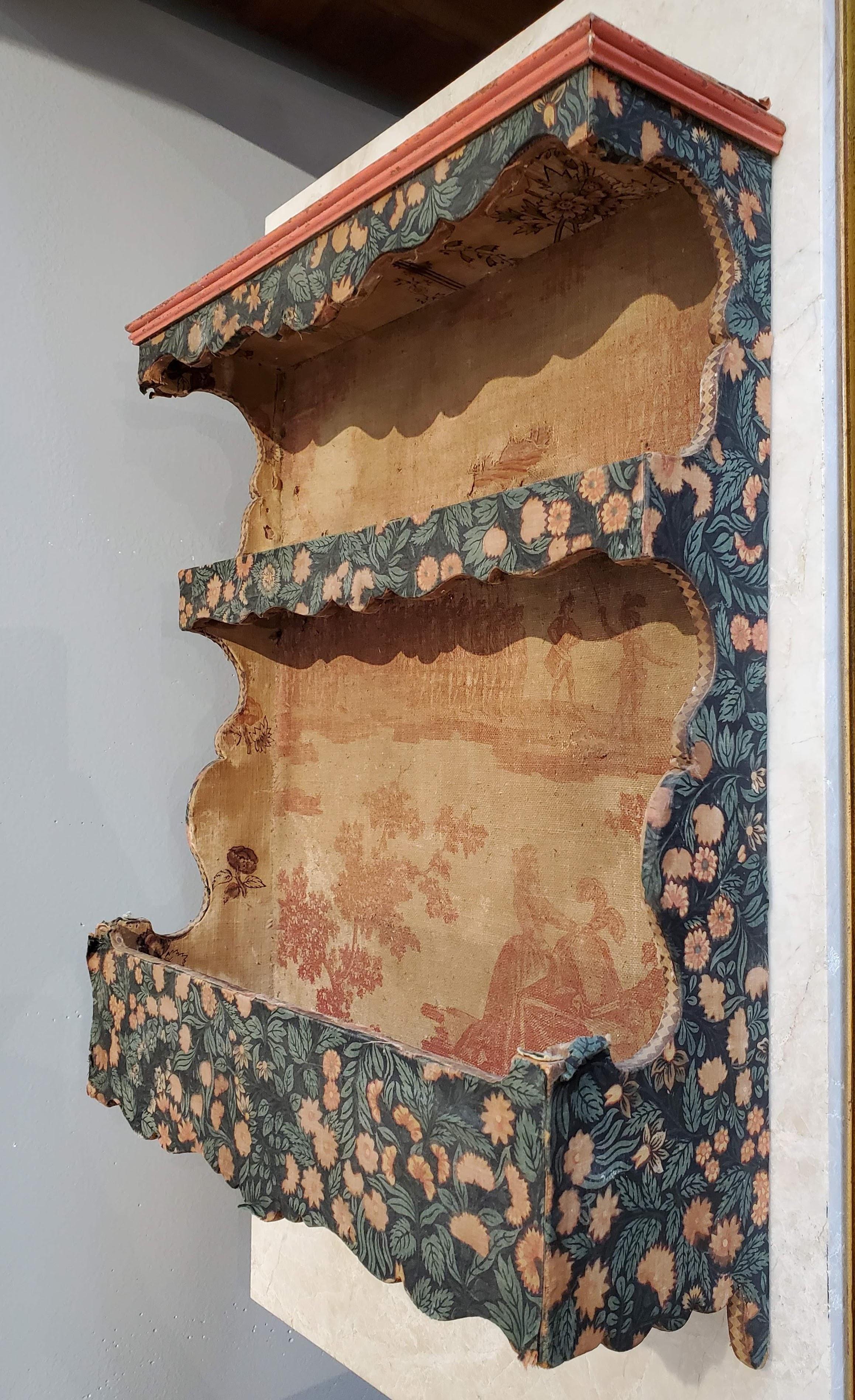 Small 19th century French Provincial spice rack with shaped cornice and sides and two shelves all covered in early 19th century toile fabric.

Provence, circa 1850.

Measures: 16