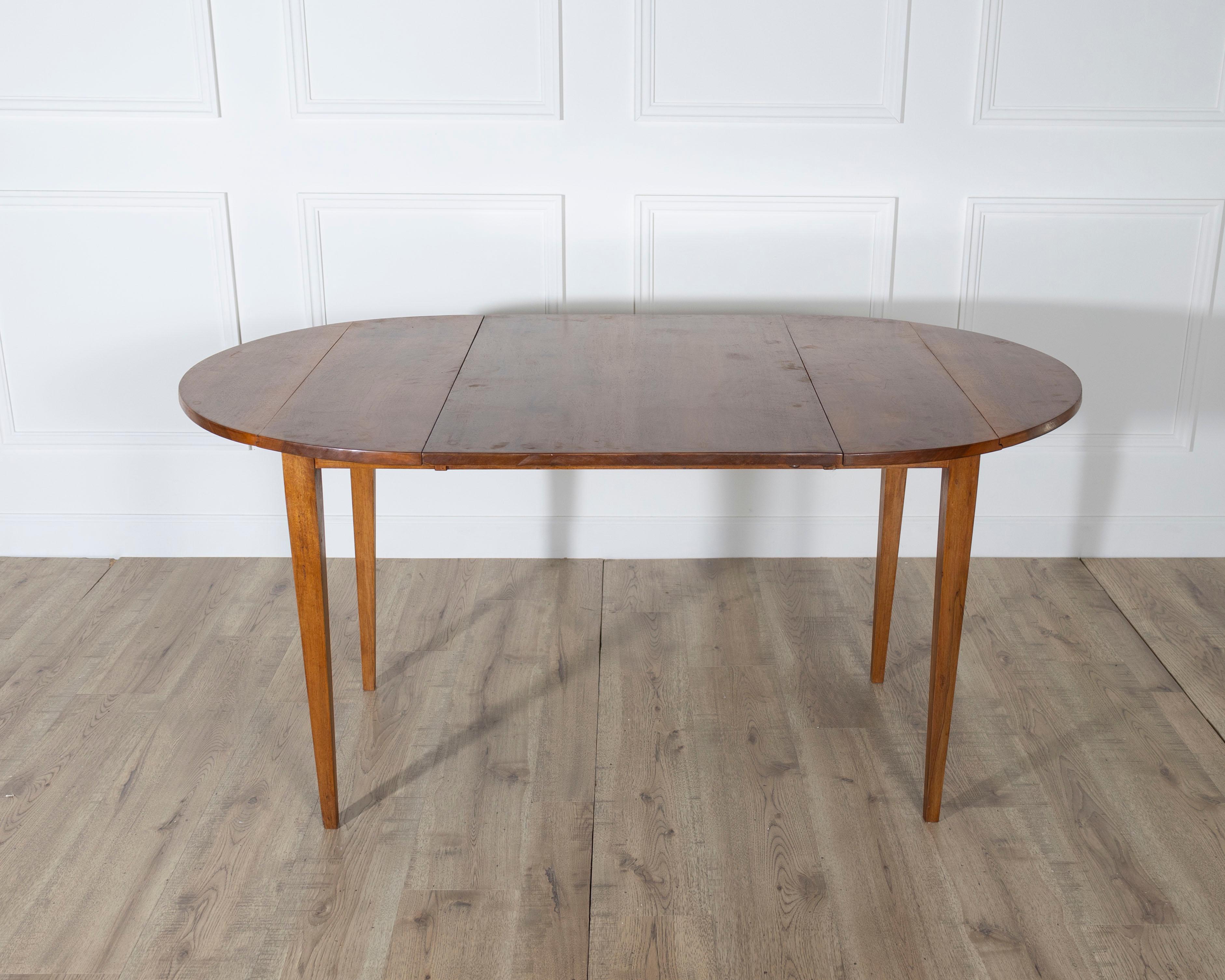 A charming and practical small 19th-century French extension table, crafted entirely in solid walnut, including its extension leaf. Modest in scale yet refined in design, the table is ideal for more intimate interiors while still offering the
