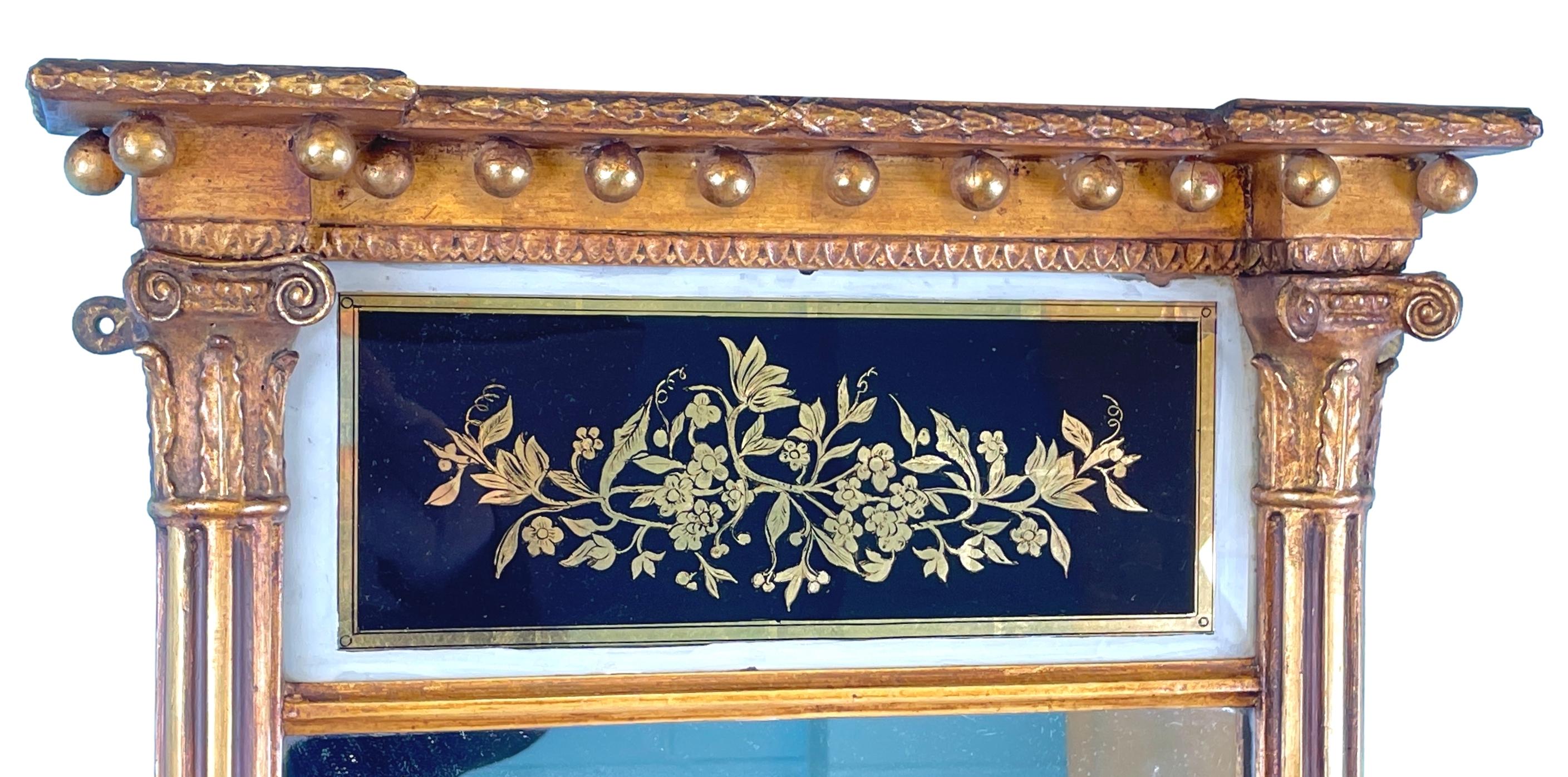 Très beau miroir à piédestal doré du milieu du XIXe siècle, de proportions inhabituellement petites, avec un élégant panneau en verre églomisé à motif de feuillage, sur une plaque de miroir d'origine flanquée d'élégantes colonnes cannelées à demi