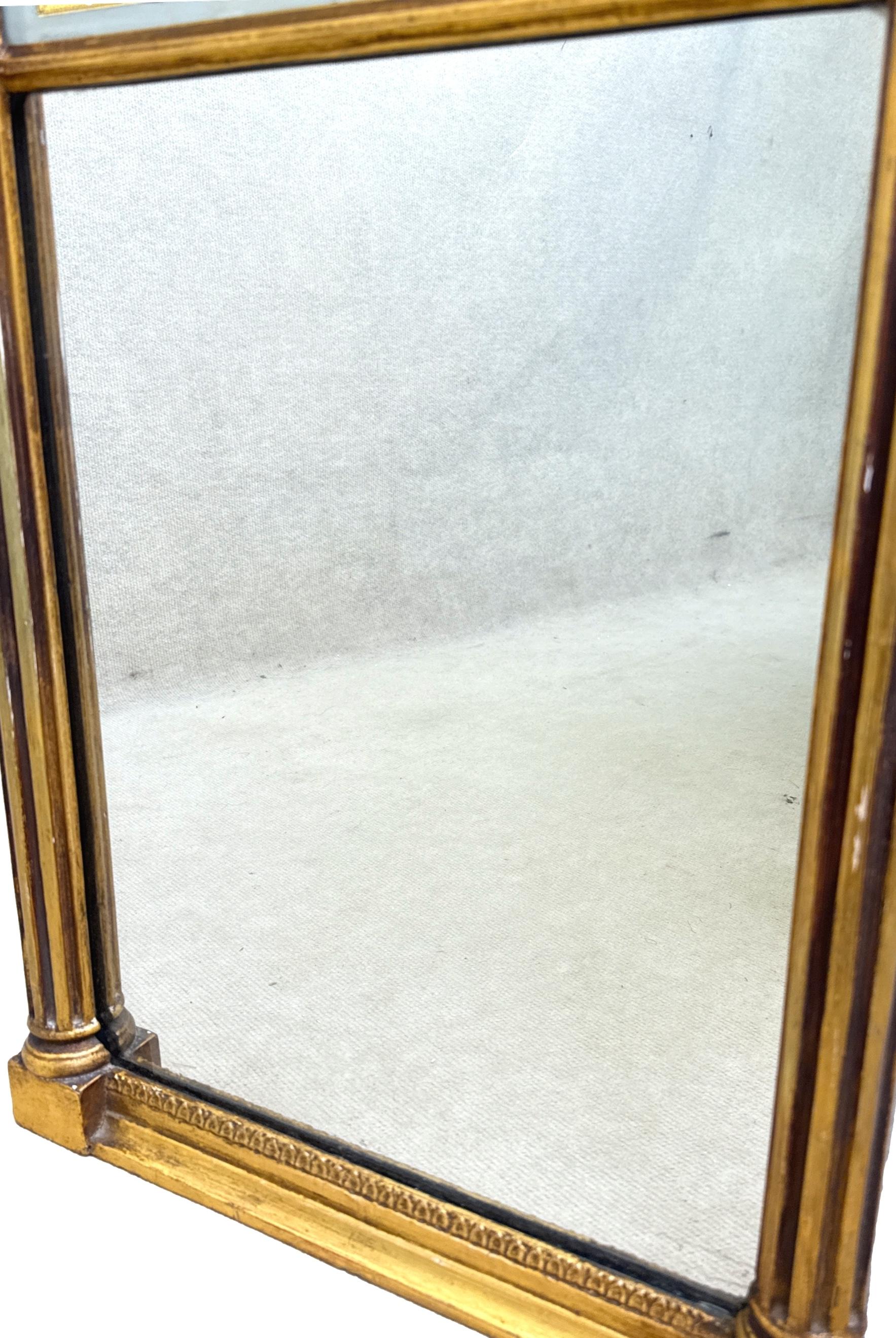 

Très beau miroir d'embarcadère doré du milieu du XIXe siècle, de proportions inhabituellement petites, avec un élégant panneau en verre églomisé à motif de feuillage, sur une plaque de miroir d'origine flanquée d'élégantes colonnes cannelées à