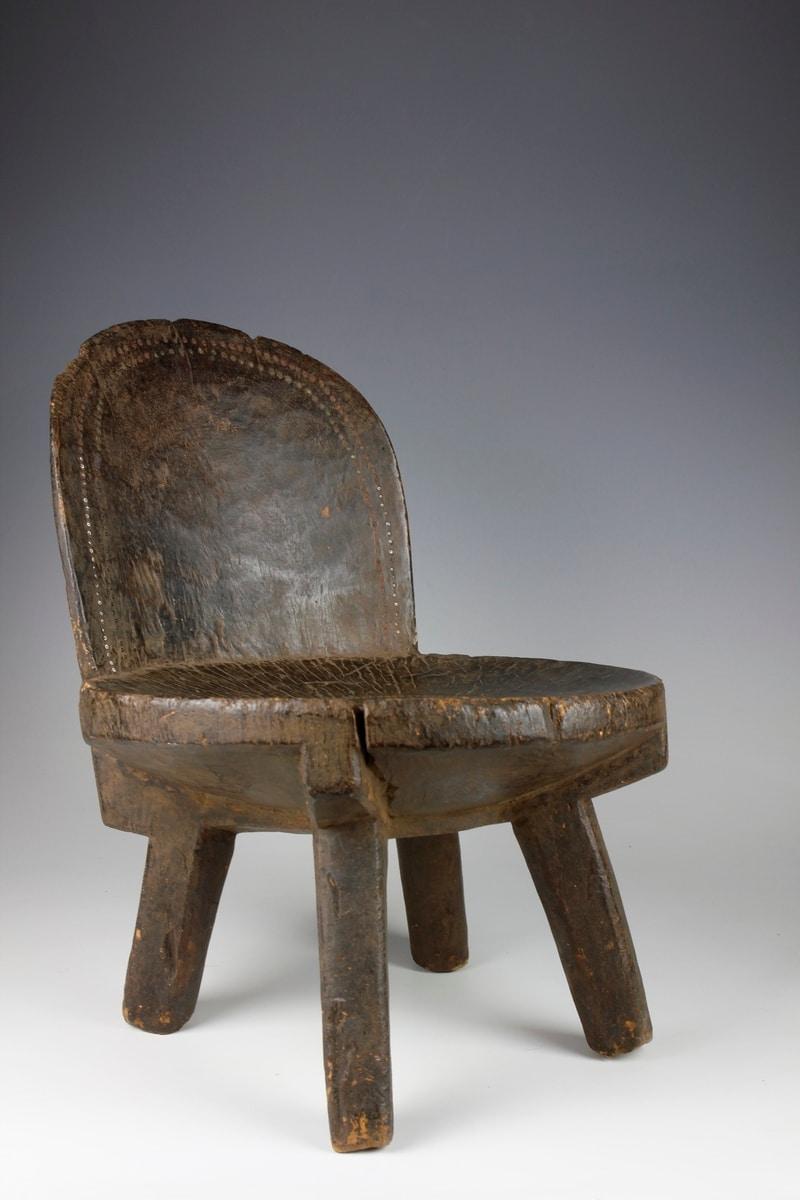 Les chaises à dossier haut, quelle que soit leur forme, sont rares au Kenya. Cette petite chaise pour personnes âgées, composée d'un dossier en forme de dôme, repose sur quatre pieds.

Le dossier de la chaise présente un motif de lézard composé de