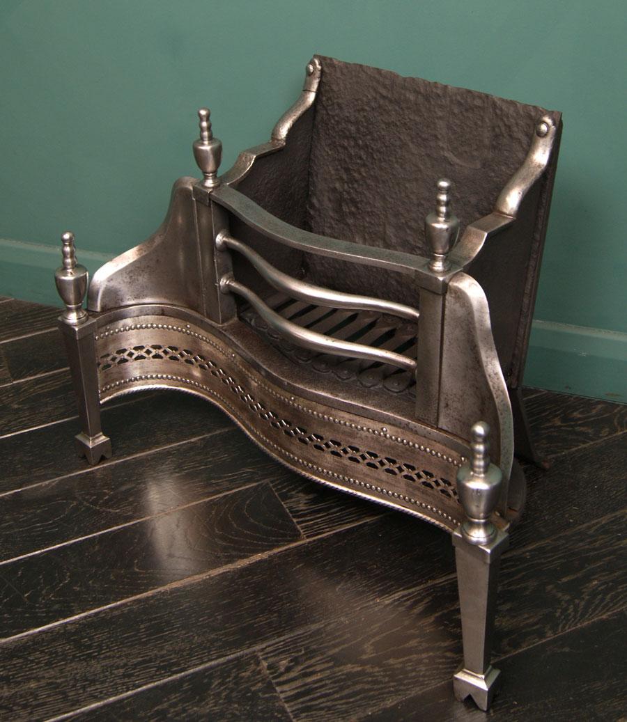 A charming 19th century polished wrought dog grate with pierced fret and tapered legs on arched-plinth feet. Rear elements include: a rivet-work grill, textured fire back and shaped sides. Restored. 
Circa 1890