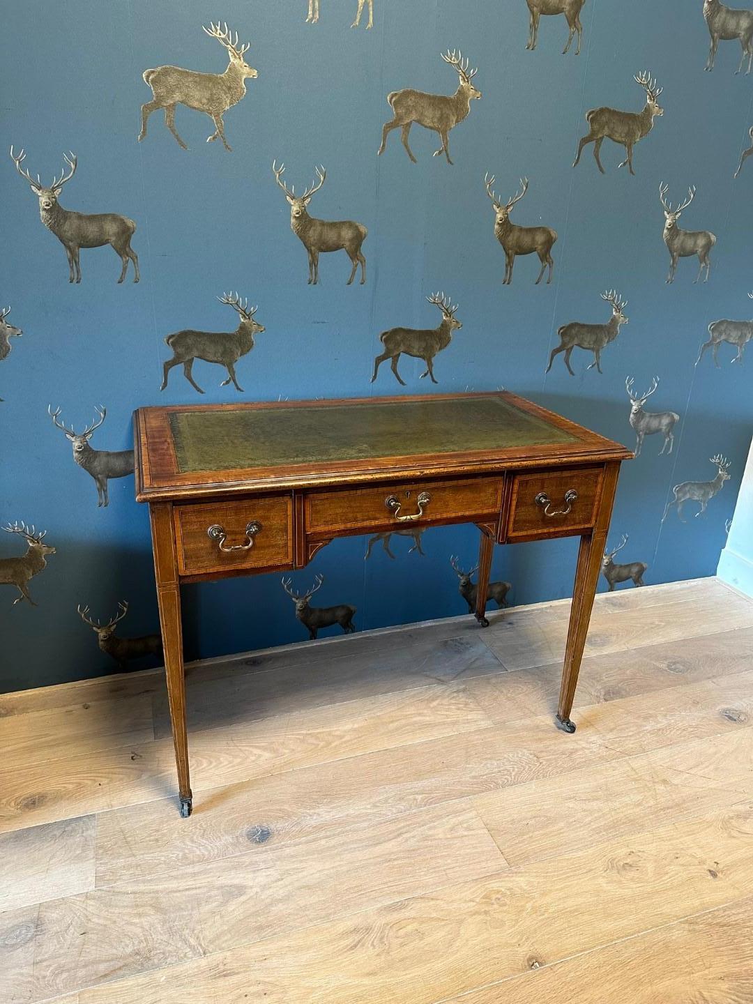 Beautiful small antique mahogany writing table with 3 drawers. The top is inlaid with green gold-edged leather. Writing table has inlay work. This is done with ebony and satinwood. The drawers are also fitted with crossbanded bleached mahogany. The
