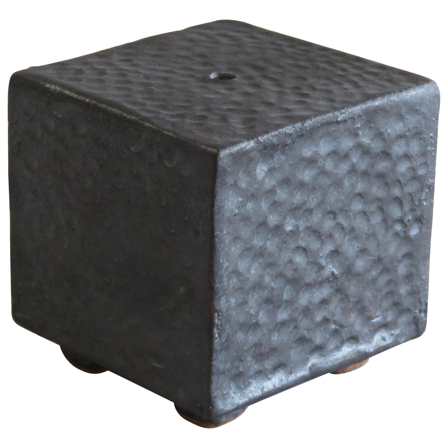 This small sculptural cube is hollow inside and stands on four small feet. Conceived as 
