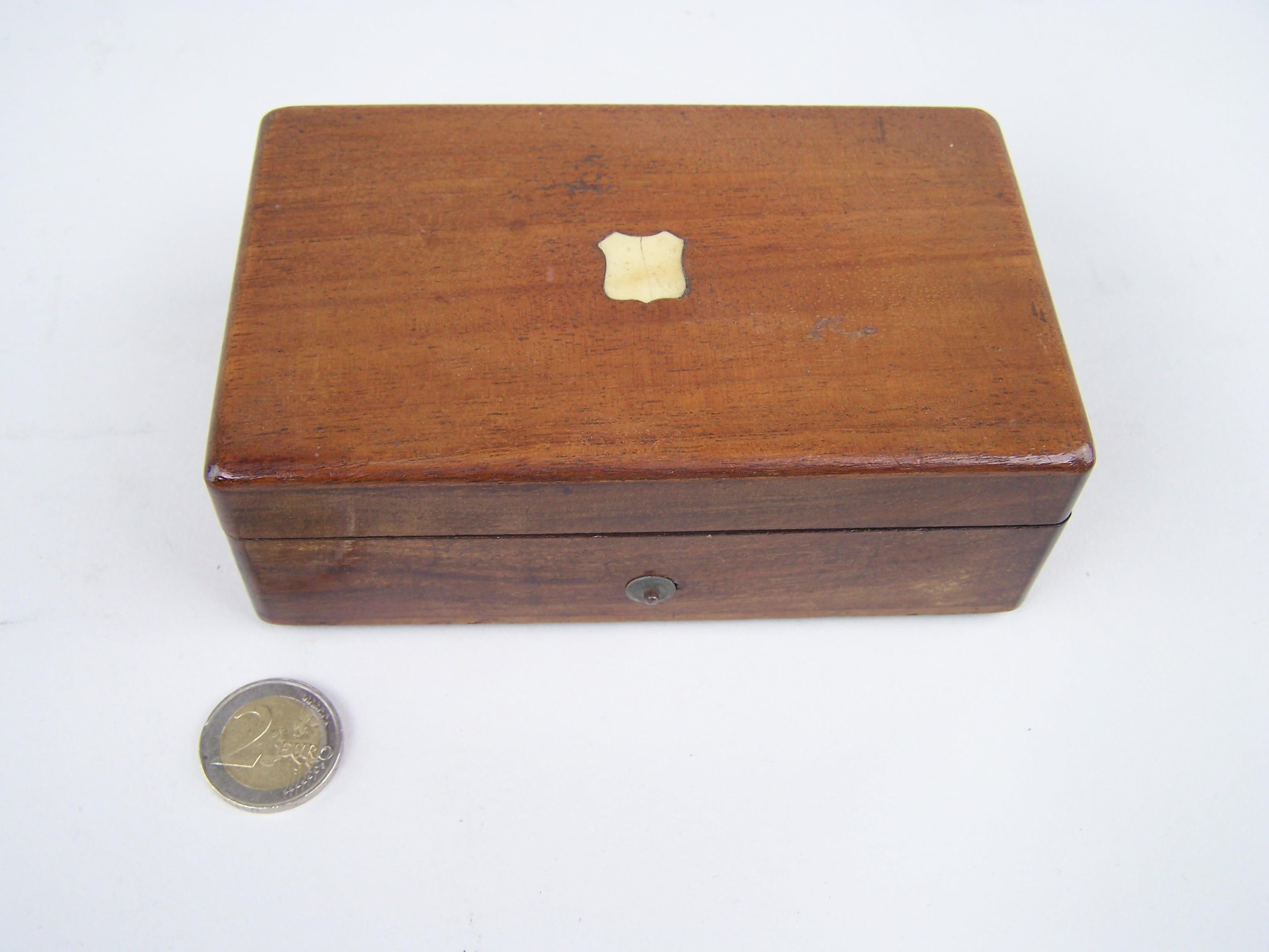 Small 3 tune mandoline music box.

The wooden case has some central inlay to the top of the lid.
The front shows the start stop lever to the right there is the change/repeat lever (disengaged). The winding is to the botom