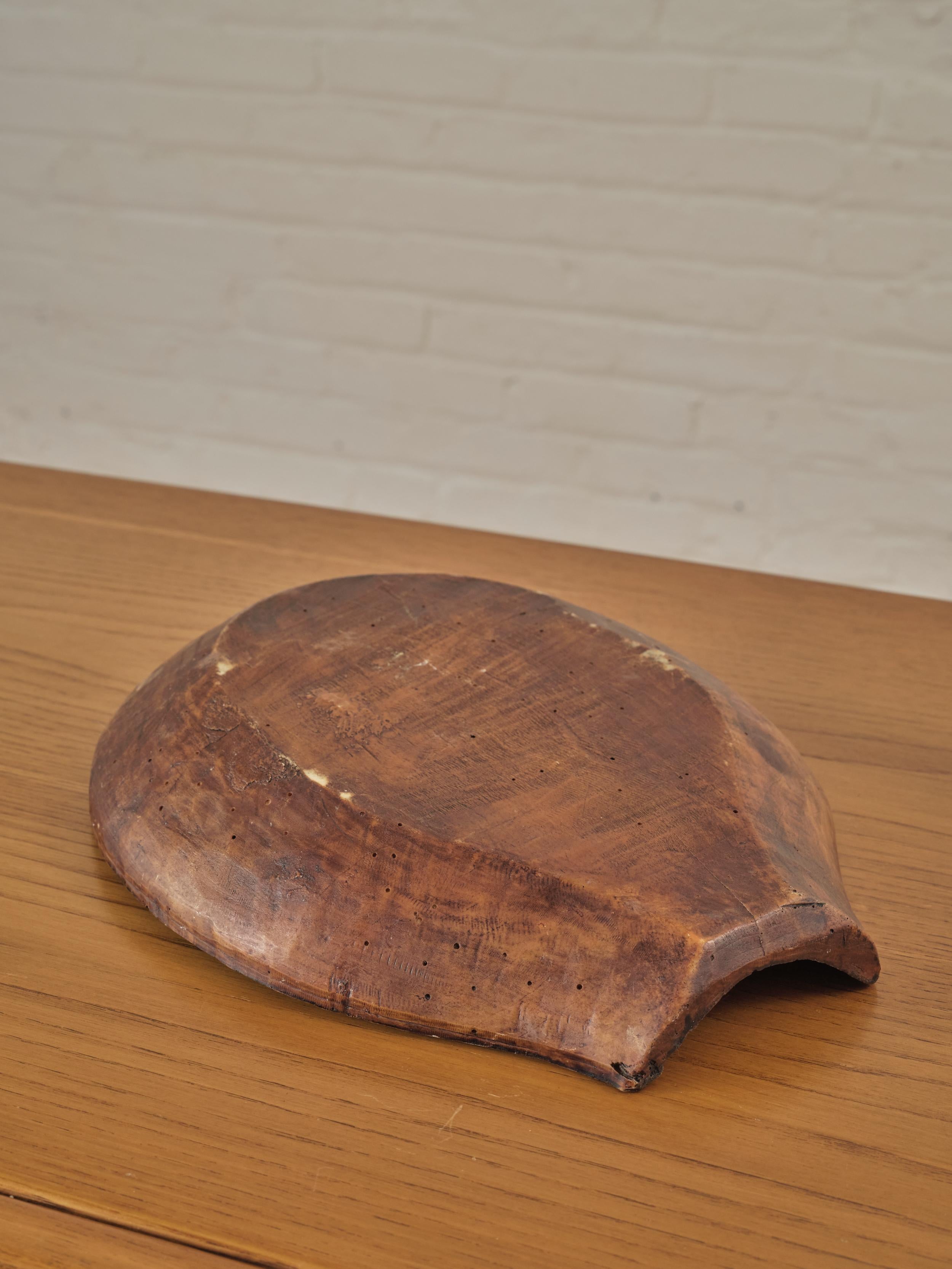 A small African wooden dough bowl with a flat opening on one side.

