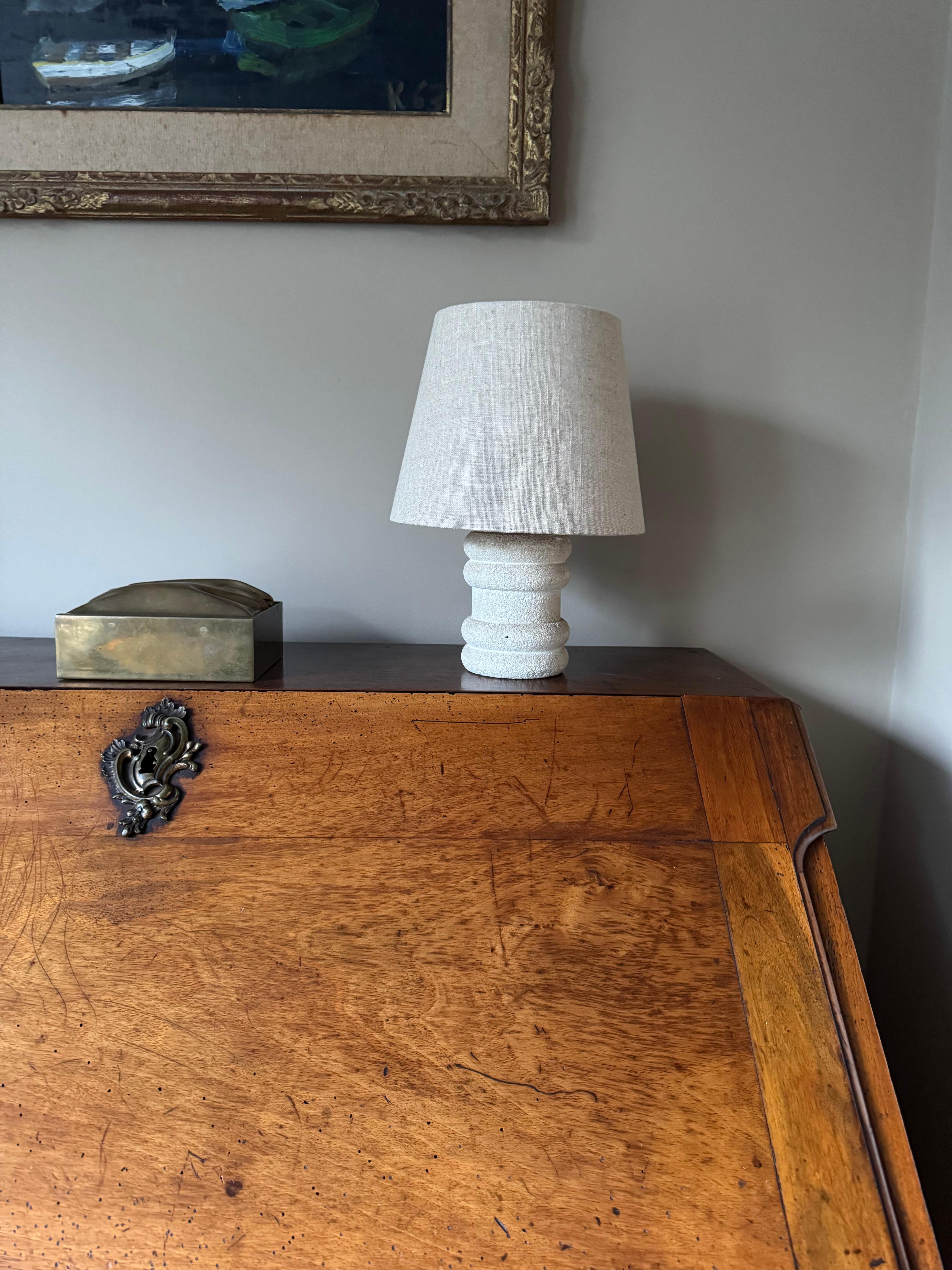 Small carved stone lamp in the style of Albert Tormos. A very similar one is also available to make a matched pair. Rewired and sold with small linen shade.