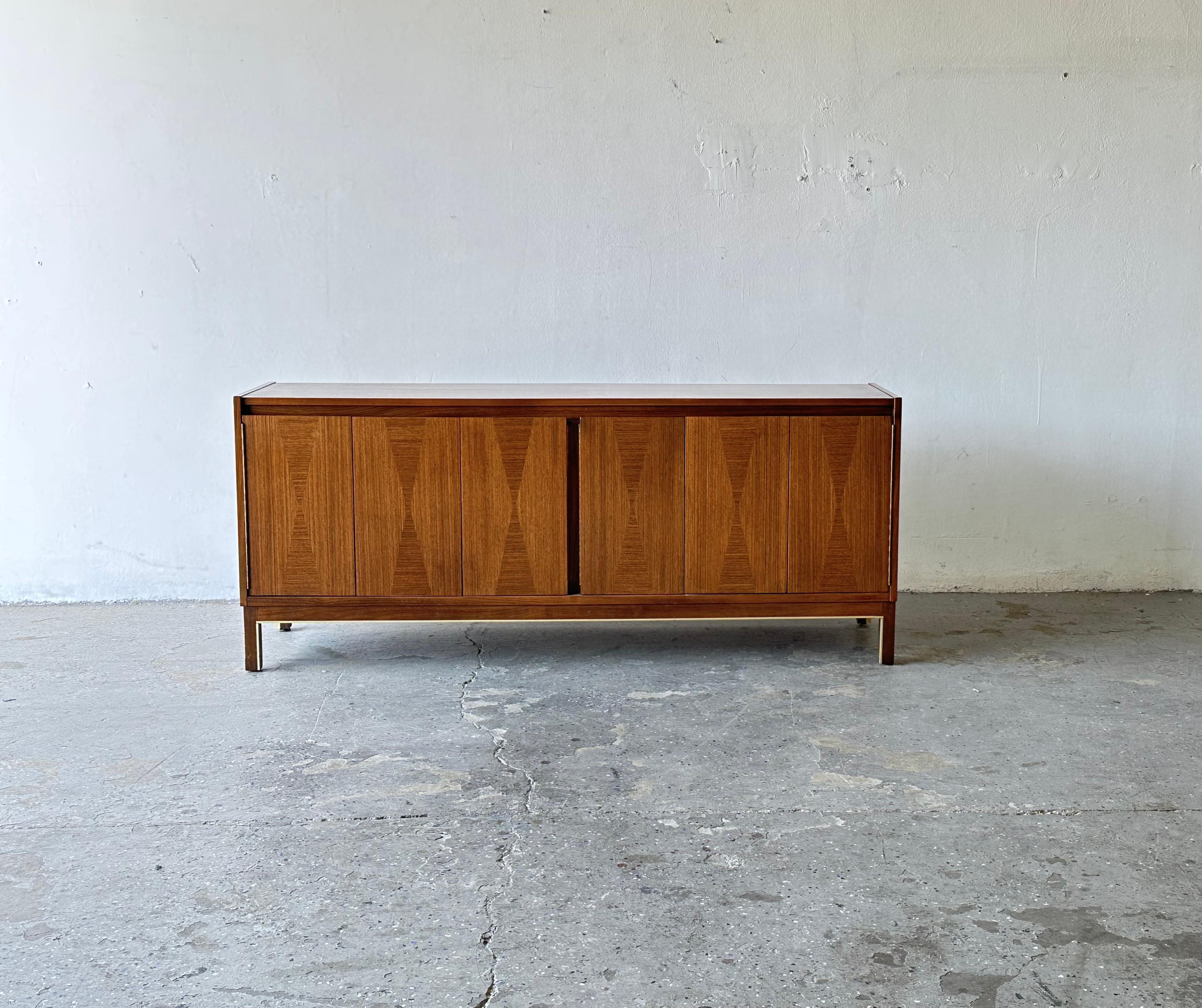 Uber cool Mid-Century Modern small credenza / Media stand by American of Martinsville. This piece has two spacious cabinets with wonderful elongated diamond inlay doors. The walnut wood grain is exquisite from every angle. Brass accents on the
