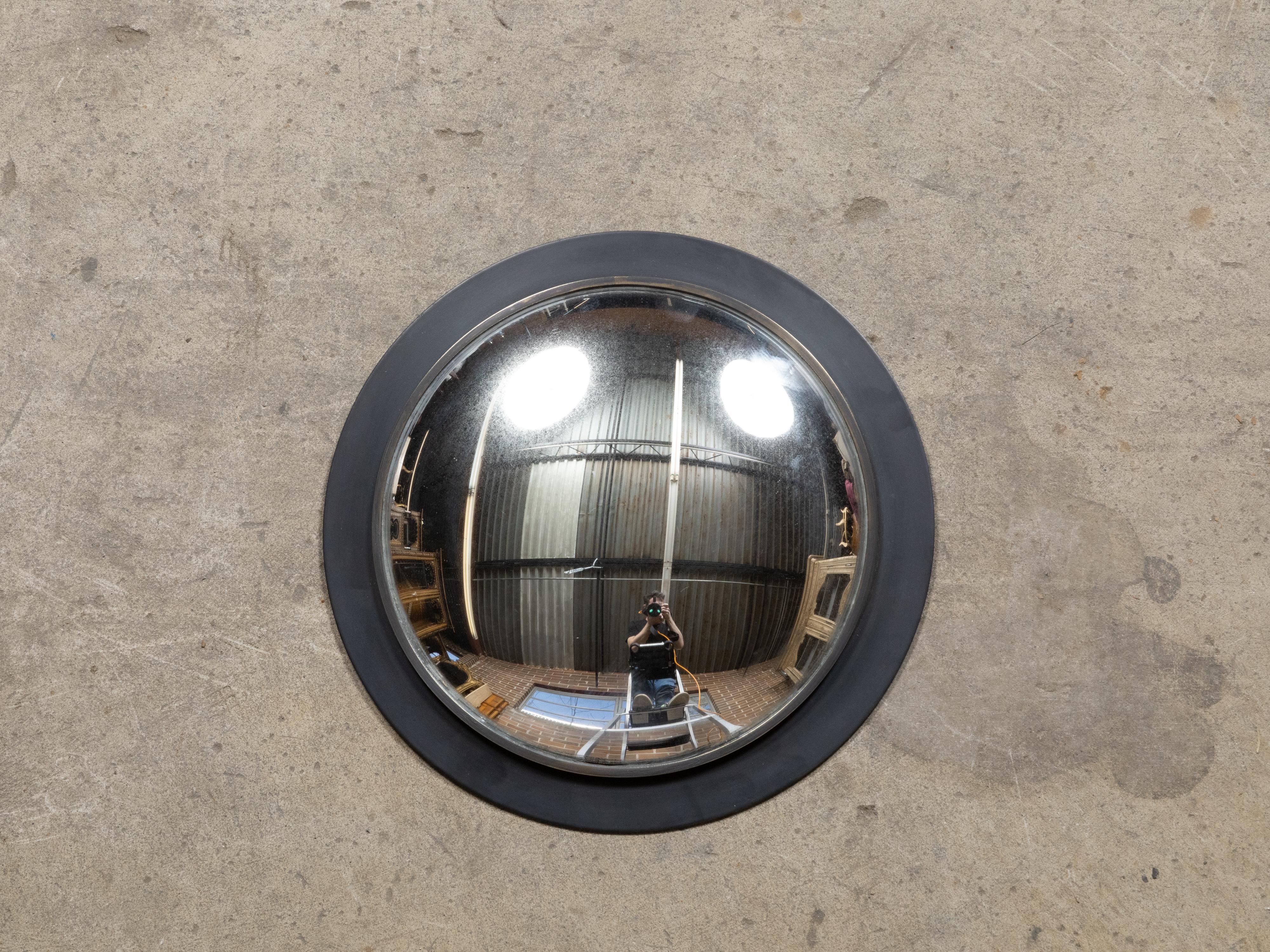 Petit miroir convexe américain vintage avec cadre circulaire noir. Fabriqué aux États-Unis, ce miroir convexe vintage séduit par sa capacité unique à déformer les images, ajoutant une touche de fantaisie et d'intérêt visuel à n'importe quel espace.