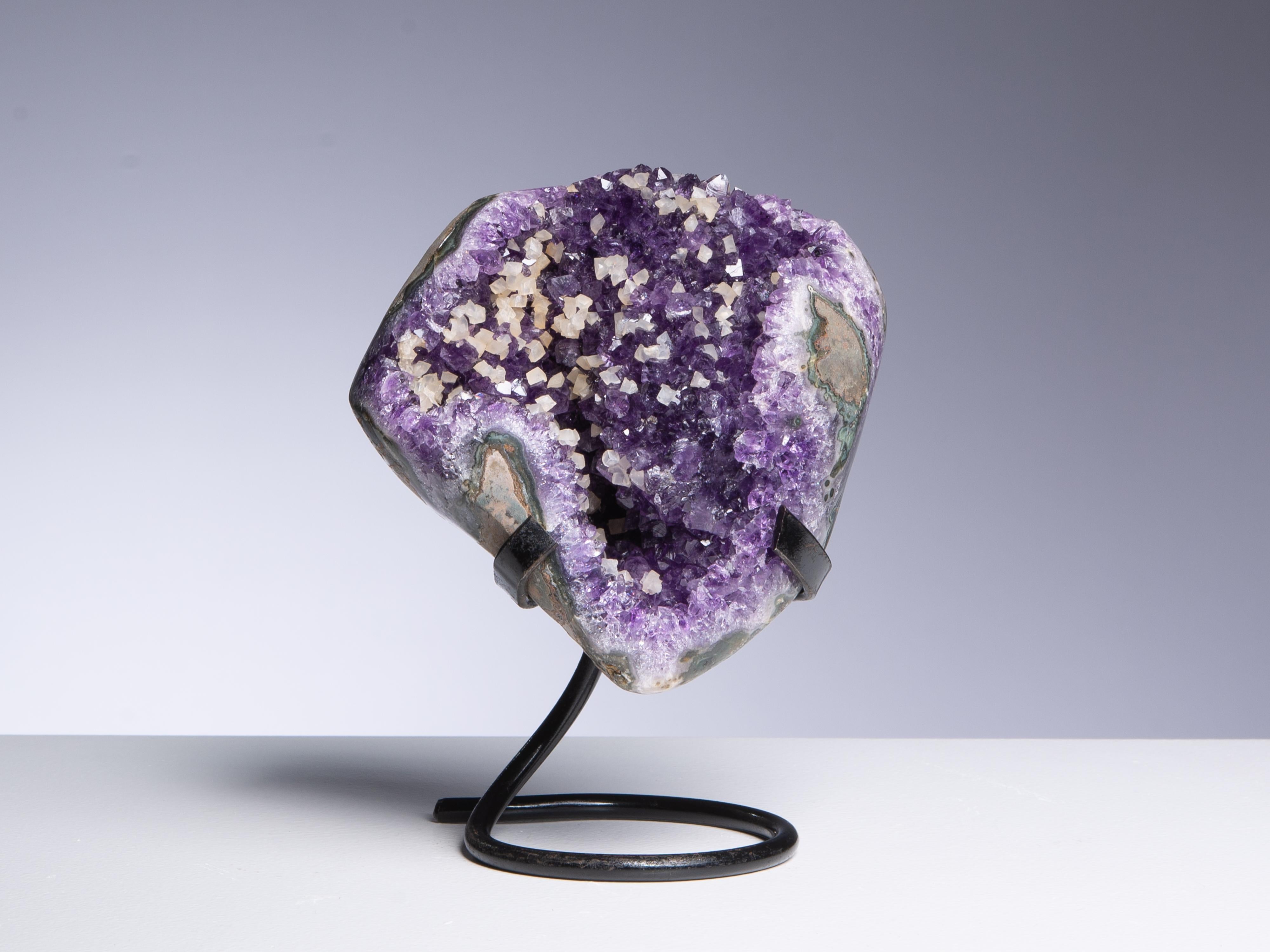 A small amethyst cluster with interesting sprinkling of creamy calcite crystals.
Polished at the edges.

This piece was legally and ethically sourced directly in the prestigious mines of Uruguay, South America. Uruguayan amethyst is internationally
