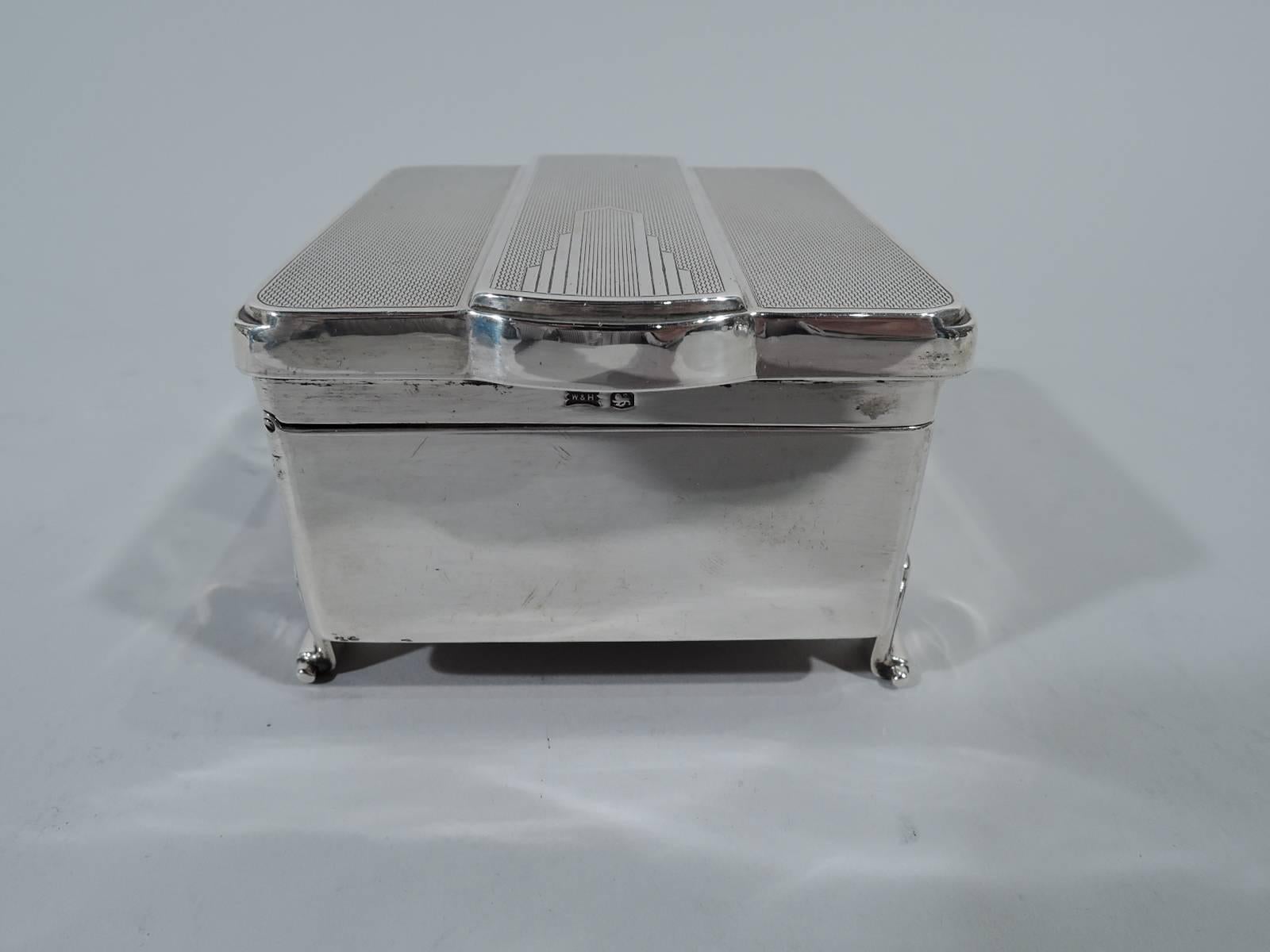 George VI sterling silver jewelry box. Made by Walker & Hall in Sheffield in 1939. Square with straight sides and four pilaster supports terminating in volute scrolls. Cover hinged with allover engine-turned ornament. Raised central strip has
