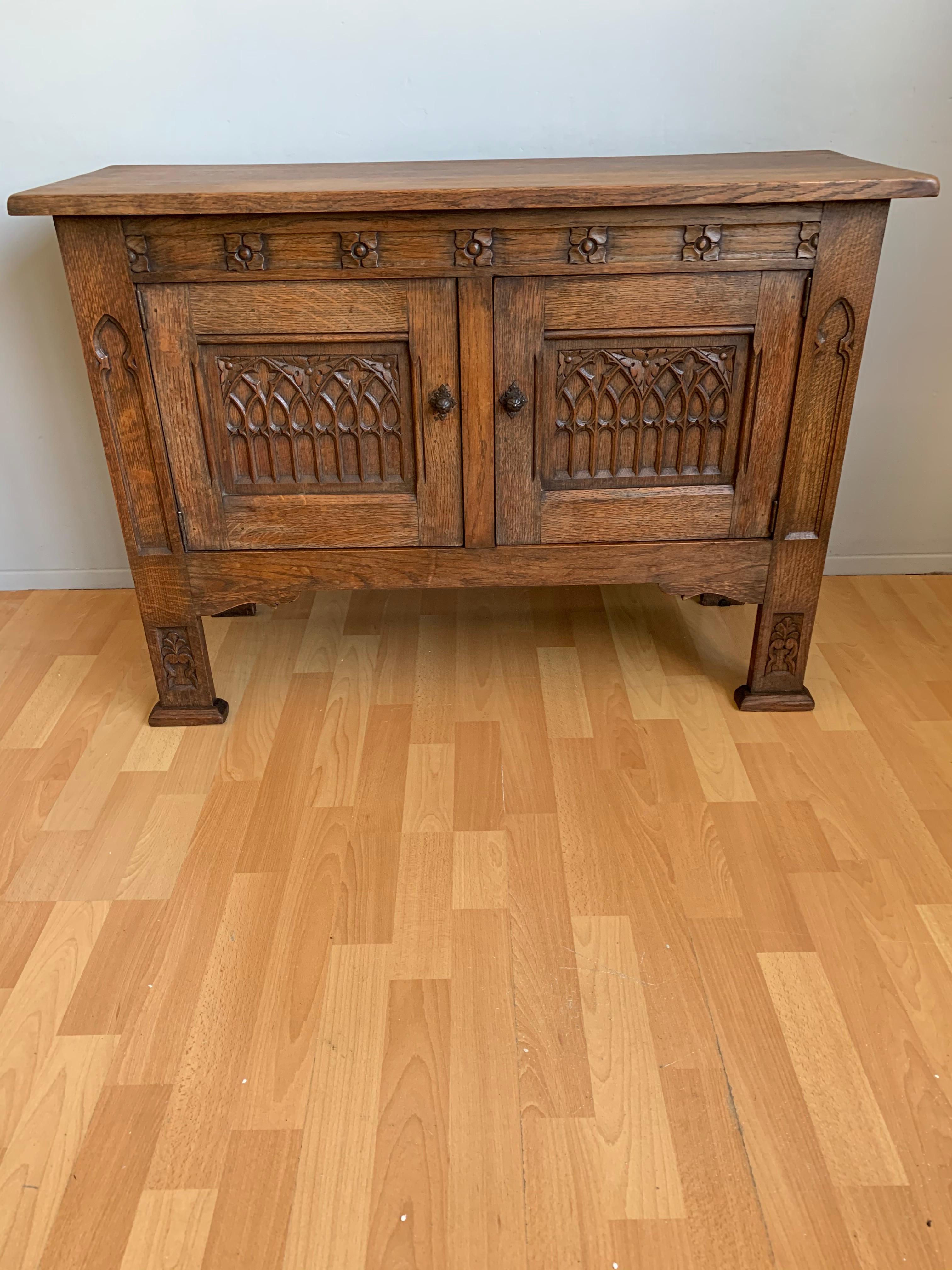 Midcentury made, solid tiger oak and small size Gothic credenza. 

This practical size and beautifully carved tiger oak cabinet from circa 1930 is in good condition. It comes with fine quality details and you could not wish for a more attractive
