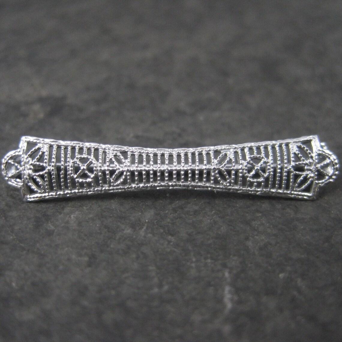 This beautiful antique filigree bar pin is 10K white gold.

Measurements: 1/4 by 1 1/16 inches

Marks: G, 10K

Condition: Excellent