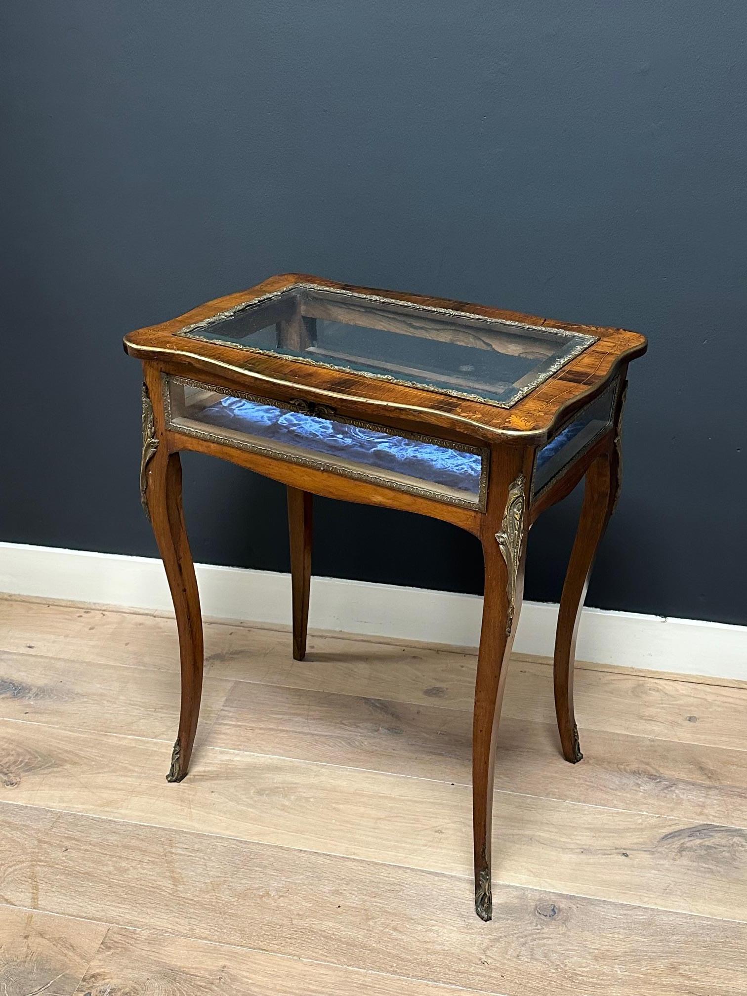 A freestanding English jewellery table made of rosewood from the late 19th century (circa 1880) with French-style marquetry. In good condition throughout.

This highly decorative table features a shaped top with original cut glass and a decorative