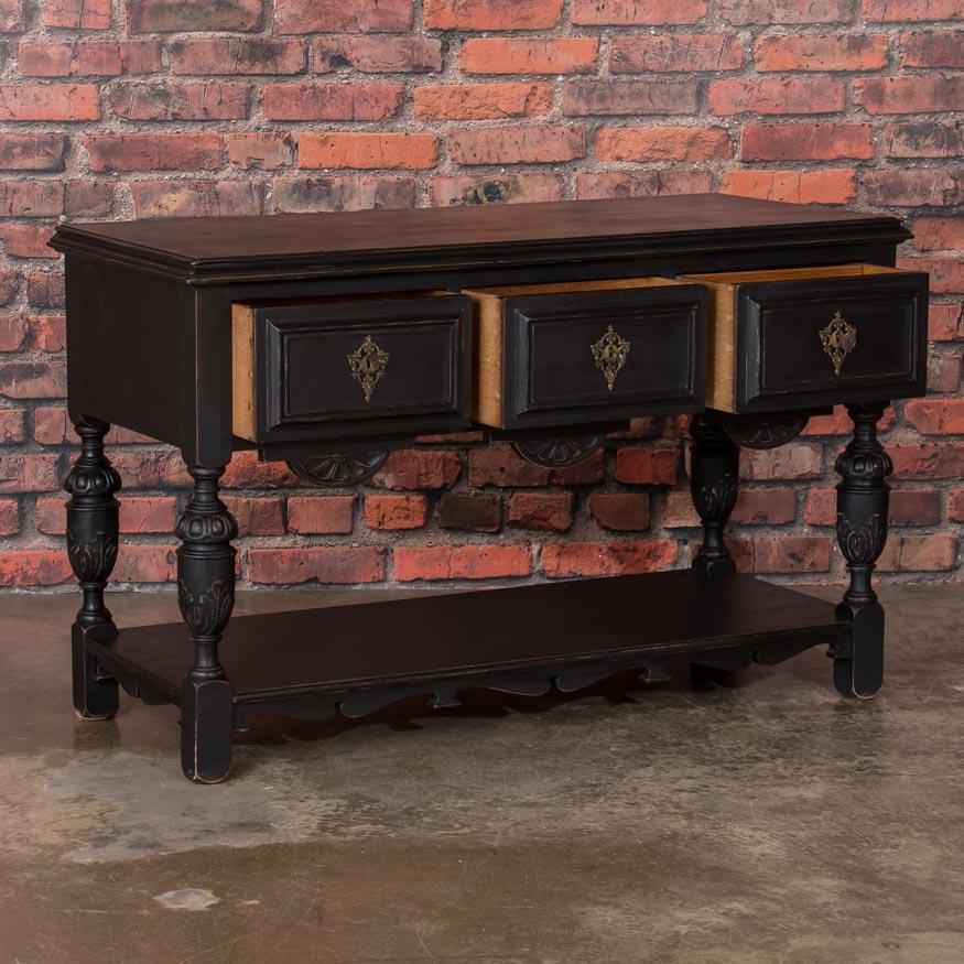 This delightful, hand carved English oak server has been given a gently distressed black painted finish, adding to the vintage character of the sideboard. The unusual configuration and small scale of this cabinet allows it to be used in a variety of