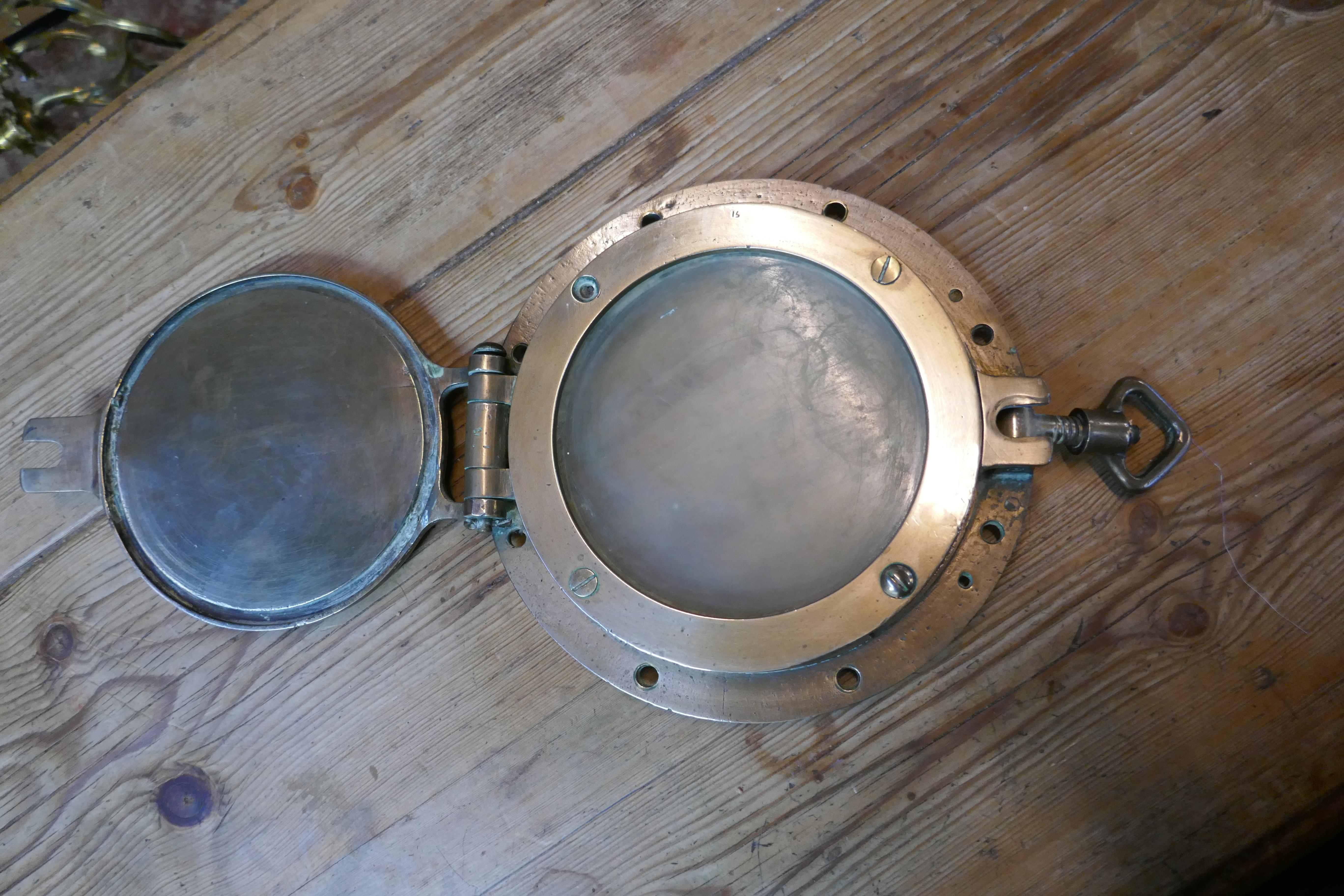 Small antique bronze brass opening porthole with deadlight

The porthole is in good condition, apart from the glass which is original and scratched 

The porthole is 9.5” in diameter
GB308.