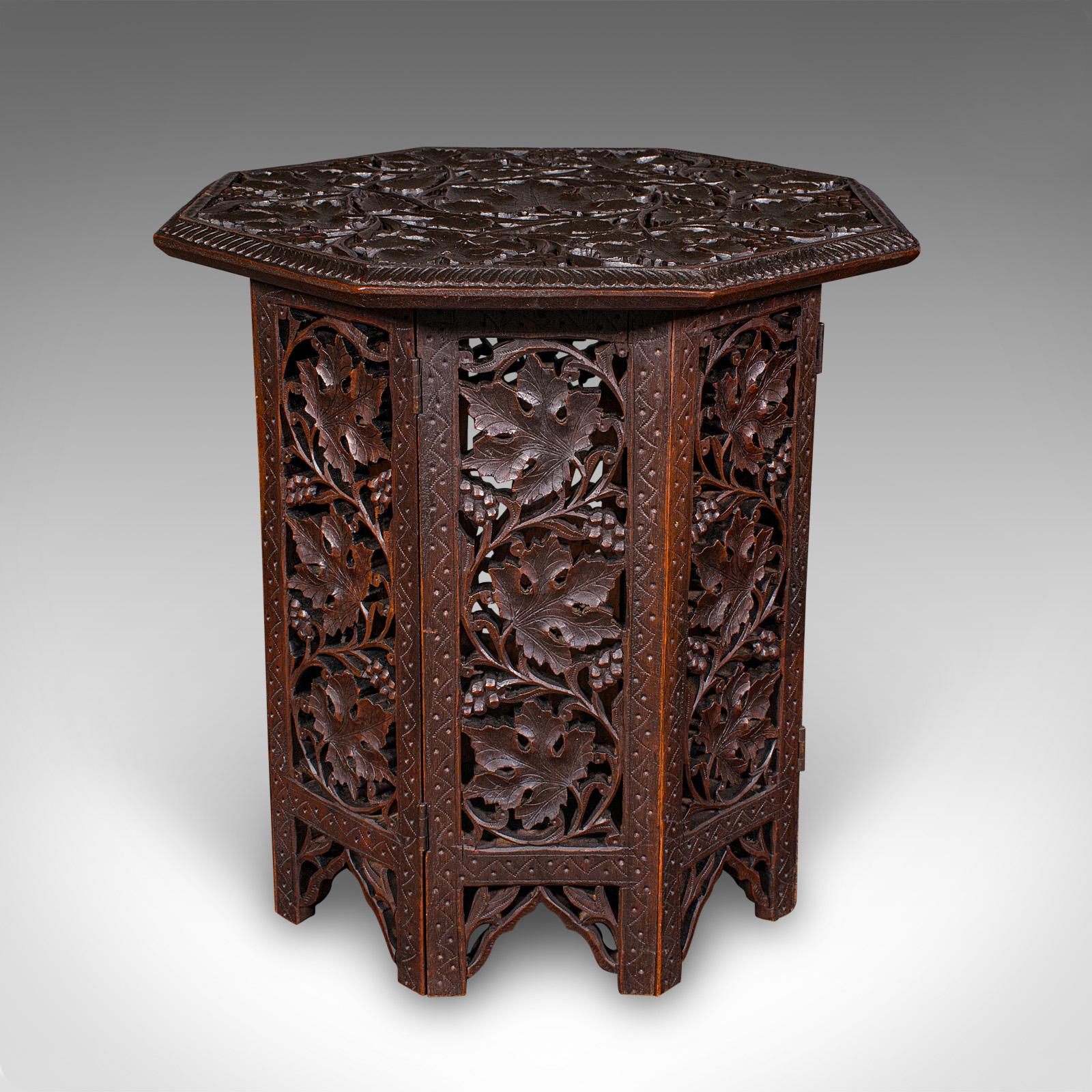 This is a small antique campaign tea table. An Anglo-Indian folding piece in richly carved teak, dating to the late Victorian period, circa 1900. Elegant and practical, this petite octagonal table offers both decorative charm and