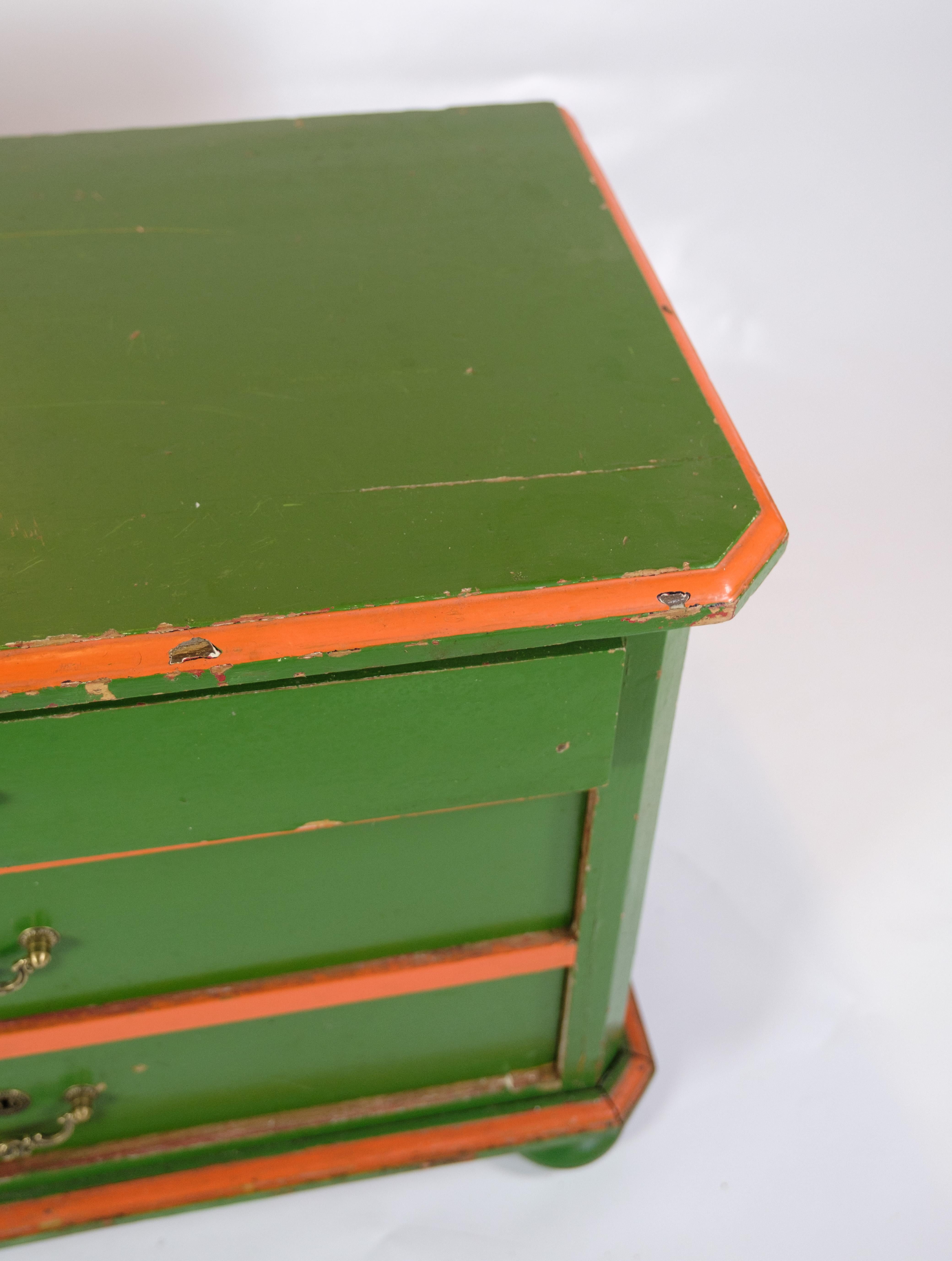 This small antique chest of drawers from approx. 1890 is a charming piece of furniture history. With its brass handles and patinated shades of green with red edges, the chest of drawers exudes a unique aesthetic and vintage charm.

The three