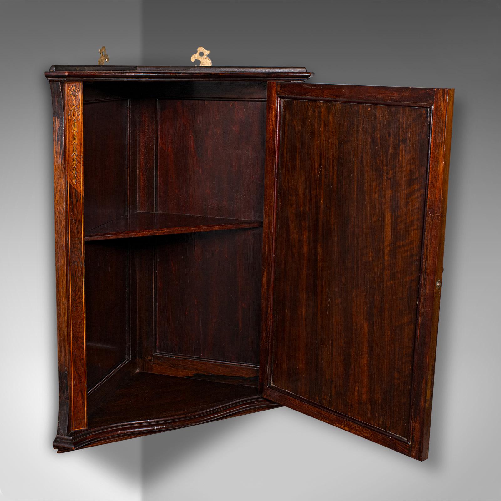 This is a small antique corner cabinet. An English, rosewood hanging display cupboard in Georgian revival taste, dating to the Edwardian period, circa 1910. A distinctive and decorative addition to the refined interior.

Elegant proportions, ideal