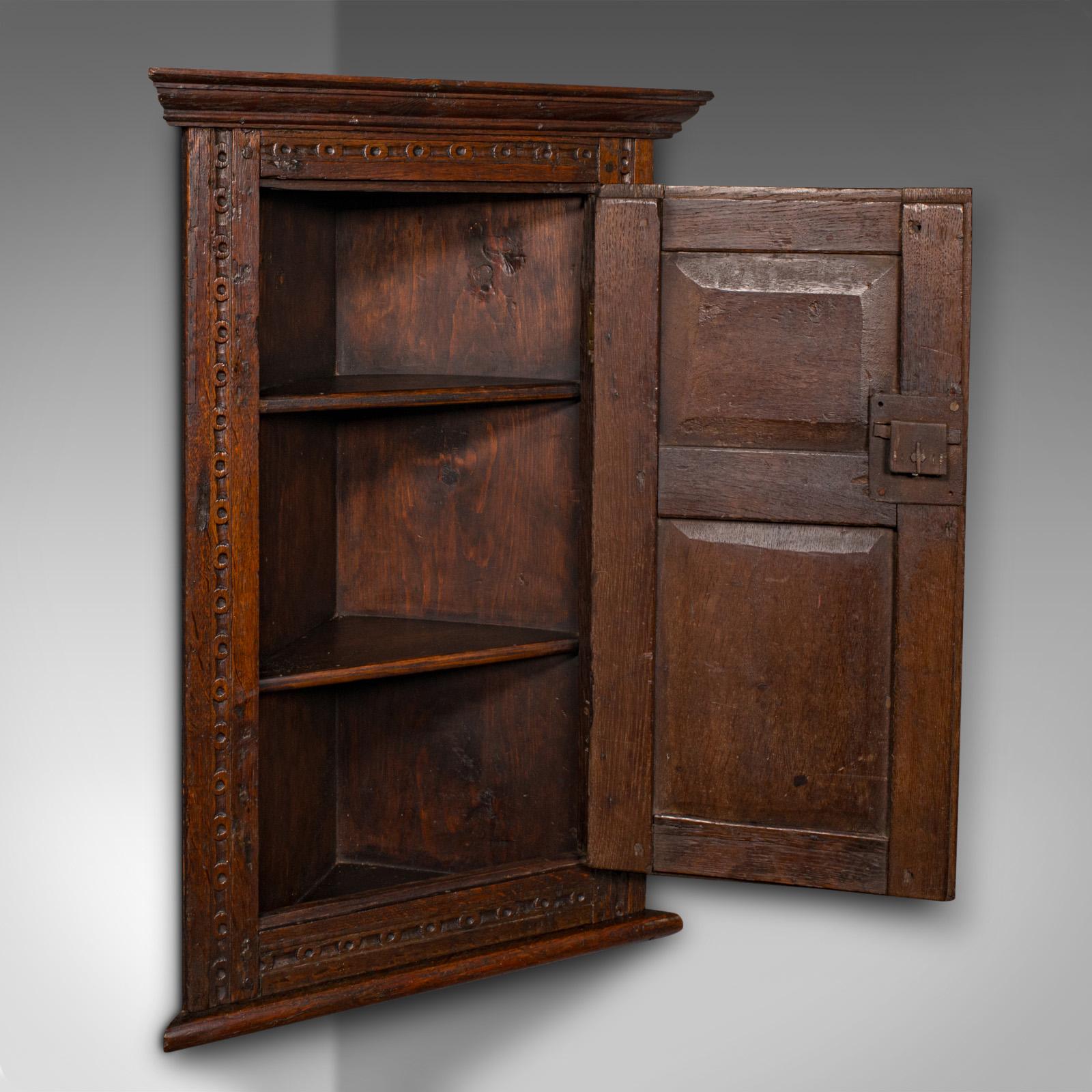 
This is a small antique corner cabinet. An English, oak wall cupboard, dating to the William & Mary period and later, circa 1690.

Appealing corner cupboard with fascinating age and finish
Displays a desirable aged patina throughout
Select oak