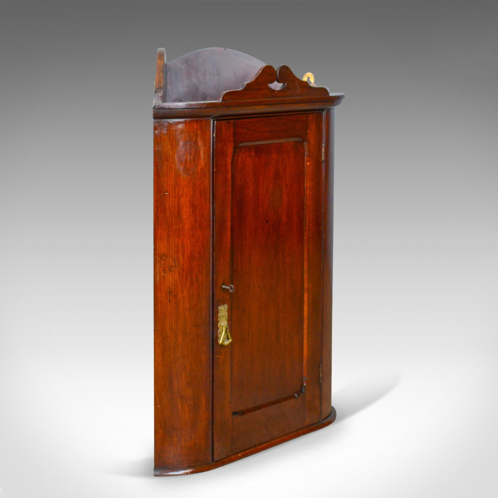 This is a small antique corner cabinet, an English, walnut, wall hanging cupboard dating to the turn of the century, circa 1900.

Attractive cabinet in smaller proportions than most
English walnut glows in the wax polished finish
Grain interest