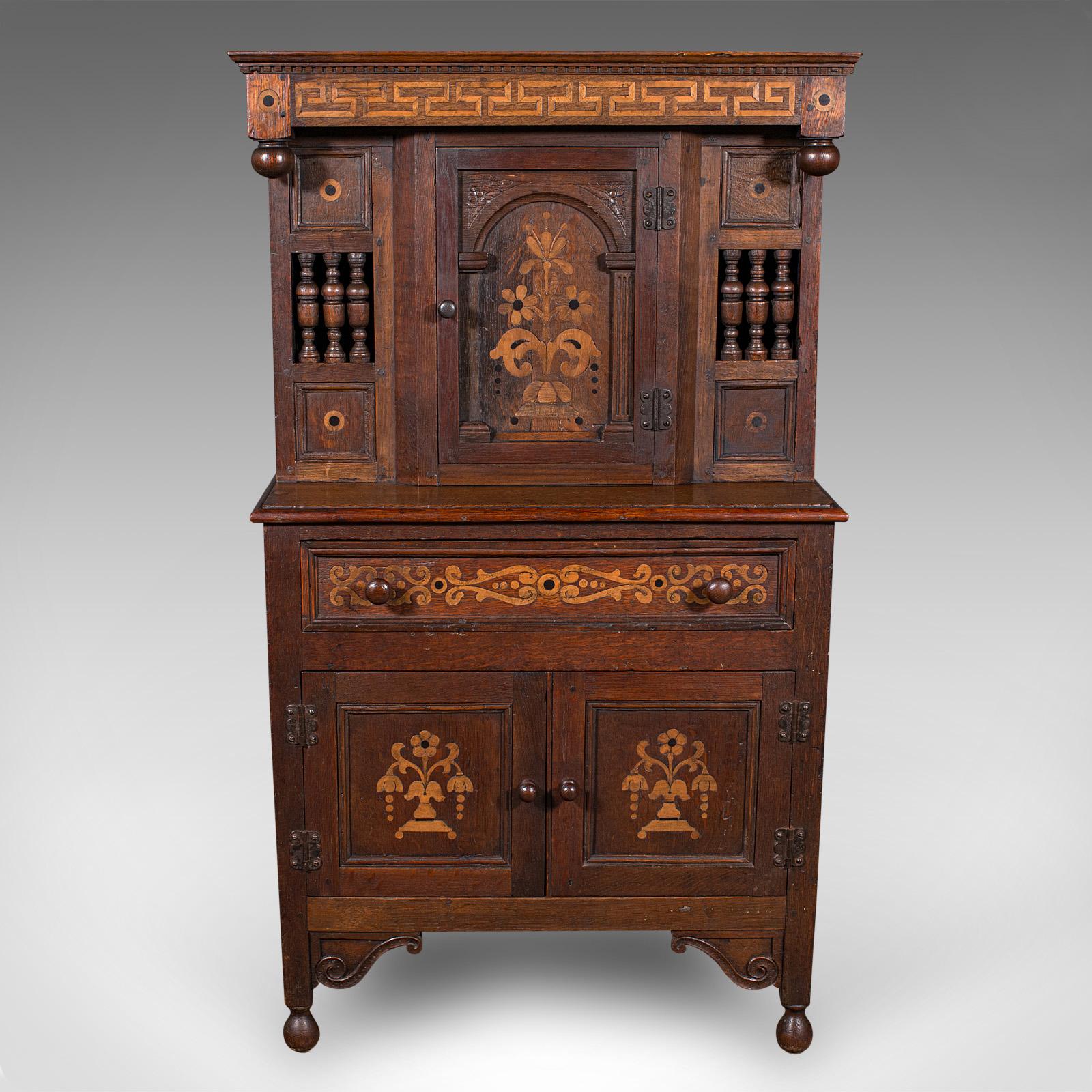 
This is a small antique court cabinet. An English, oak and boxwood side cupboard with superb revival taste, dating to the 17th century and later.

Wonderful revival court cabinet, of delightfully diminutive proportions at just 4' tall
Fascinatingly