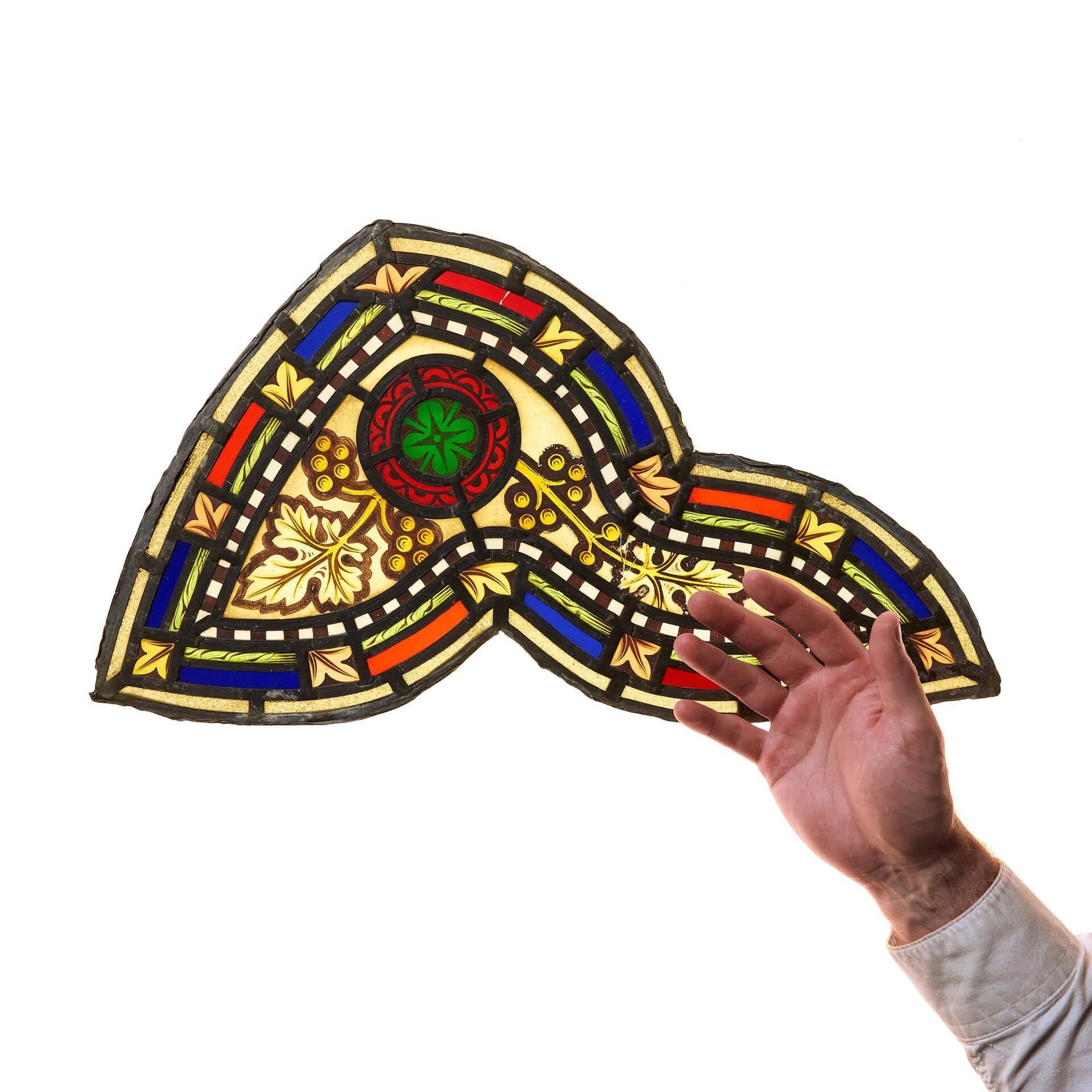 A small antique stained glass panel in ecclesiastical style dating from the Victorian era.

In an irregular shape and intricately detailed with differing shades of stained glass scrolling foliage and various shades of vivid colours.

Likely once