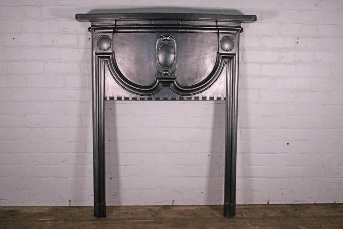 Small antique Edwardian cast iron fireplace surround. The serpentine shelf is edged with bead and bar detail. Above the bow fronted fireze and slender jambs, circa 1900.

This surround has been finished with traditional black grate polish, leaving