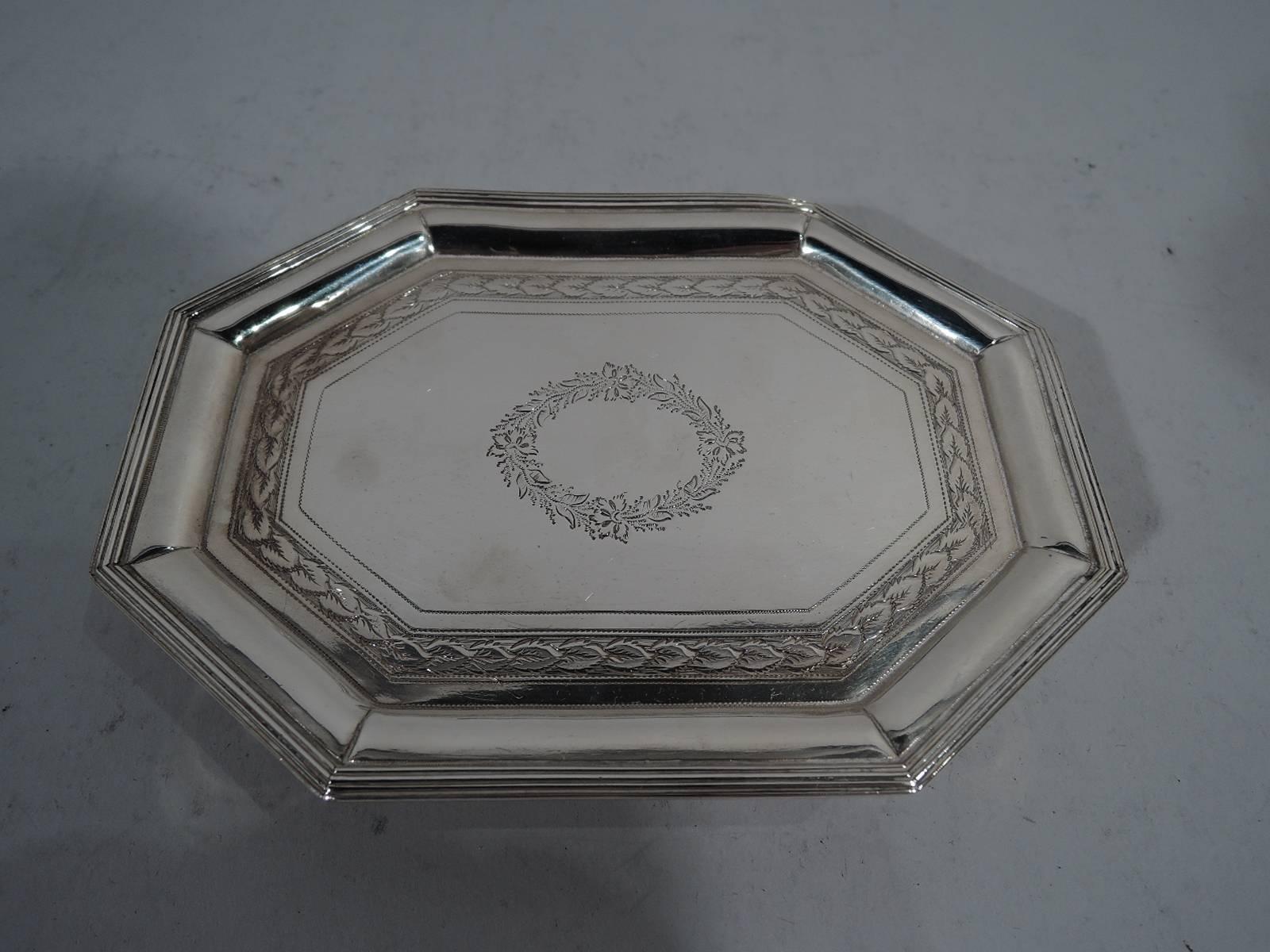 George III sterling silver salver. Made by Turner & Williams in London in 1802. Rectangular with chamfered corners and four tapering supports. Ornament engraved in well: central wreath (vacant) and imbricated leaf and pointille borders. Reeded rim.