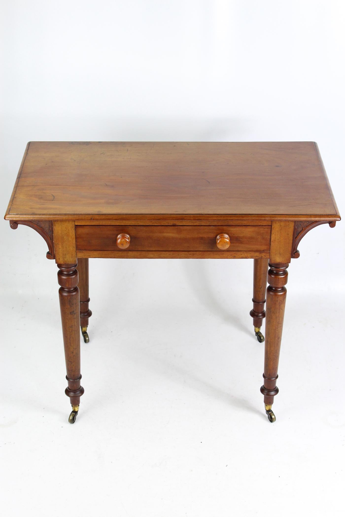 A good quality small antique Victorian mahogany writing table or desk with a single drawer dating from circa 1870. In mellow well-figured mahogany it stands on elegant turned legs with brass cup casters. With an over sailing top supported by carved