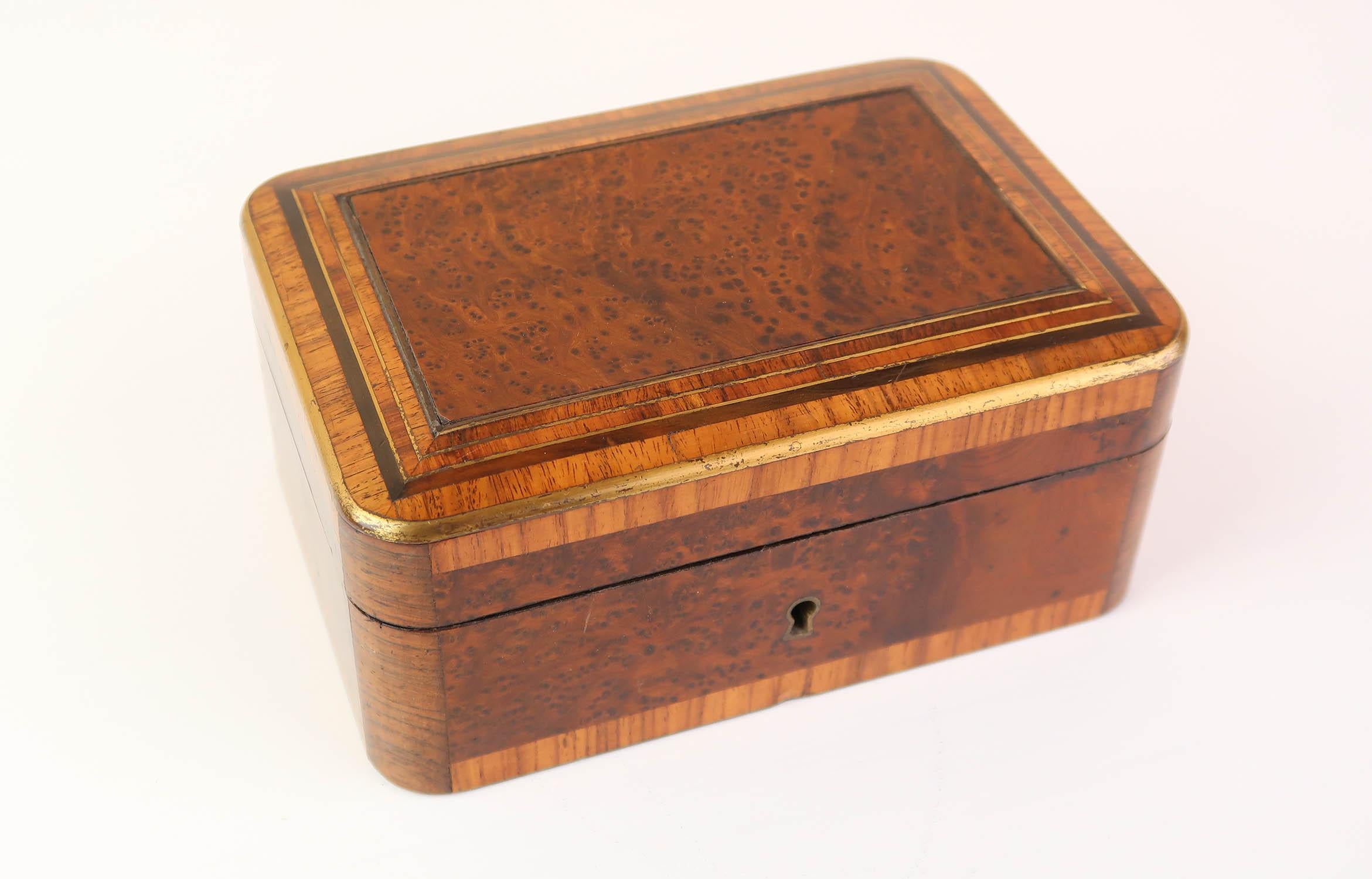 Lovely quality jewlelry box

Veneered in exotic woods. Possibly amboyna, kingwood and burr yew. With brass inlay

Fabulous colour and figure in the wood

Original blue silk interior.

With key.

Dated 1877 on the underside.



