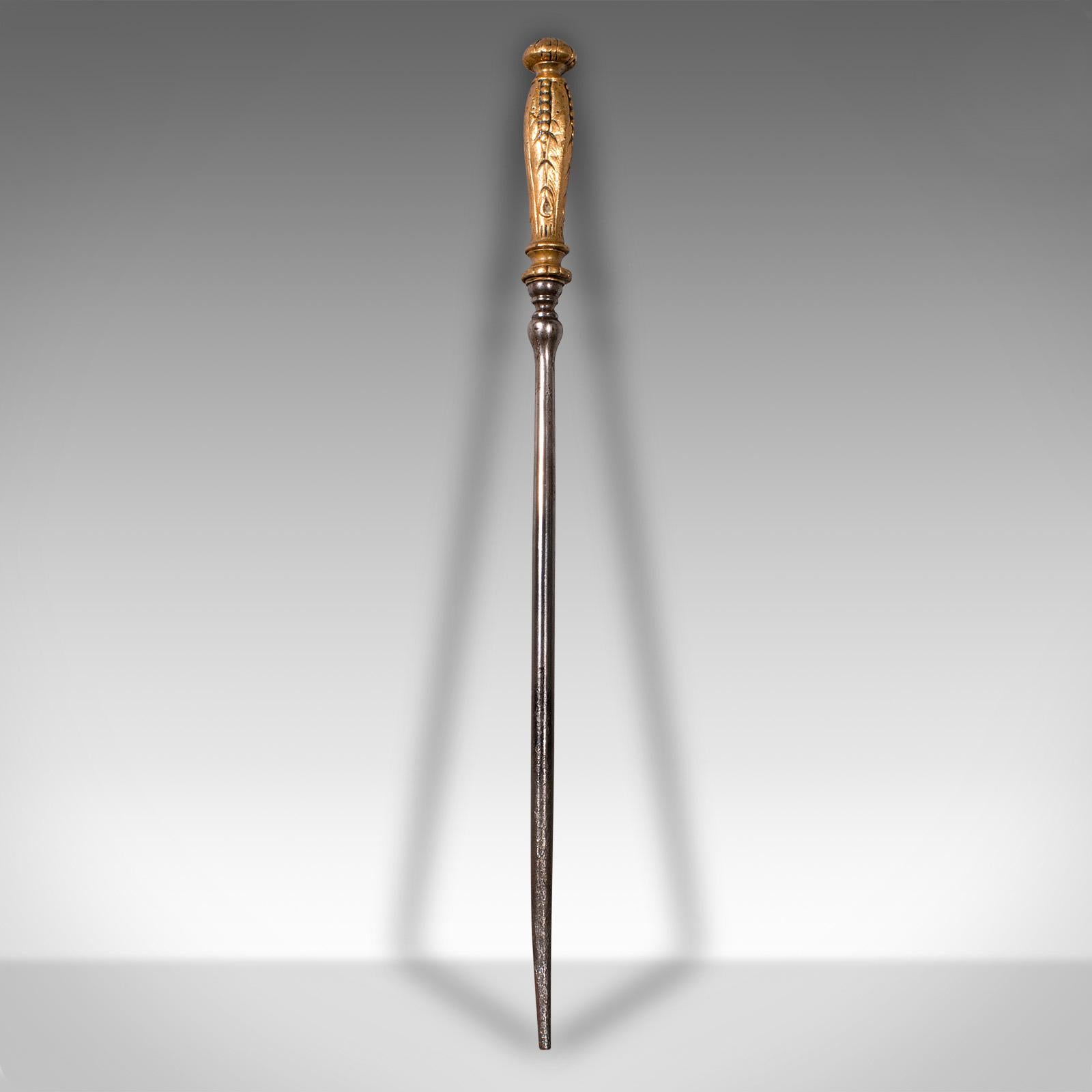This is a small antique fire poker. An English, cast iron and brass decorative fireside tool, dating to the Georgian period, circa 1800.

Of petite form and beautifully weathered
Displays a desirable aged patina and in good original