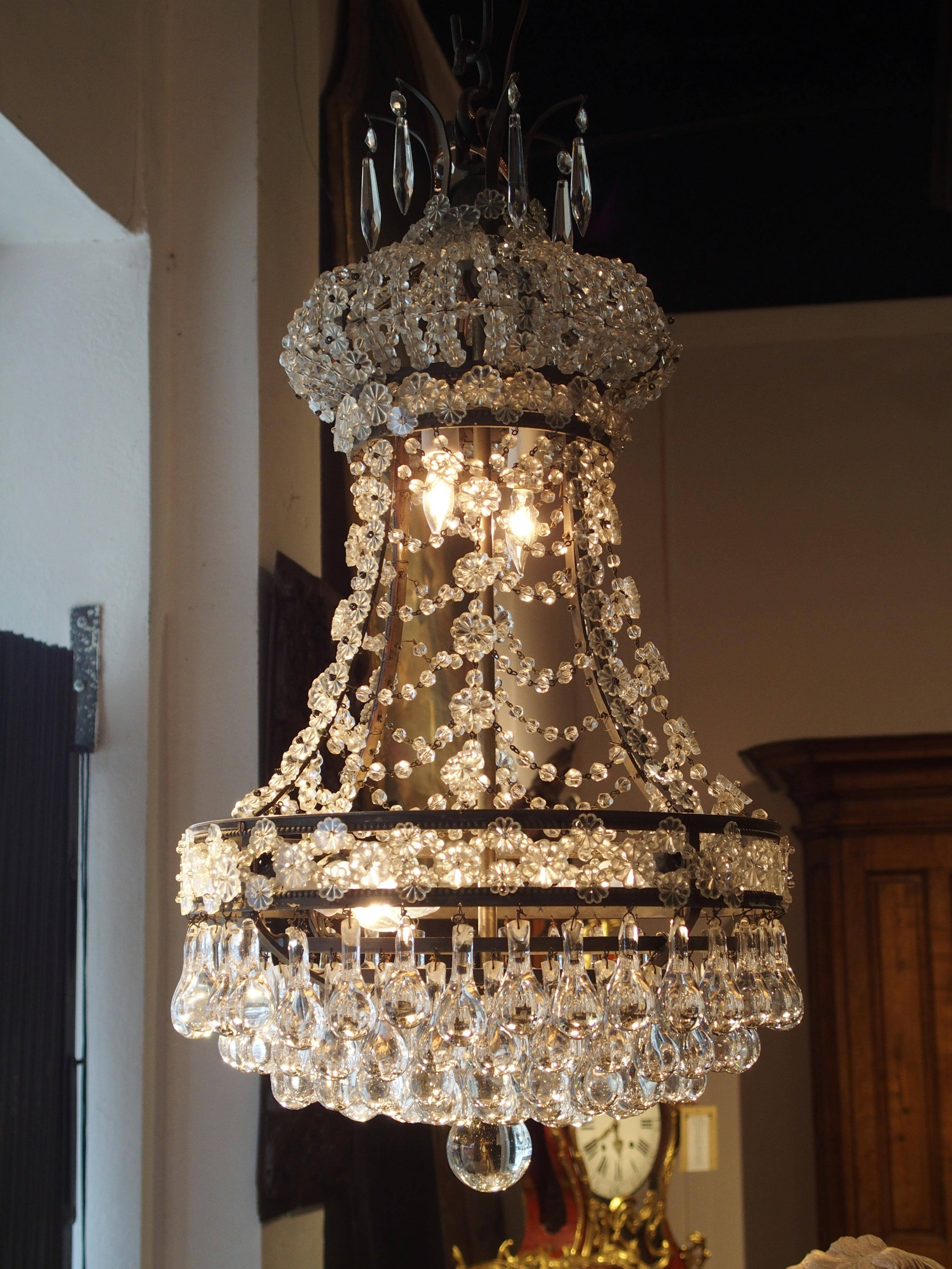 This small Louis XVI style crystal chandelier was made in France during the latter part of the 19th century. The lovely chandelier has four lights in the base and two in the canopy. The crystal pendeloques have been arranged to elegantly reflect the