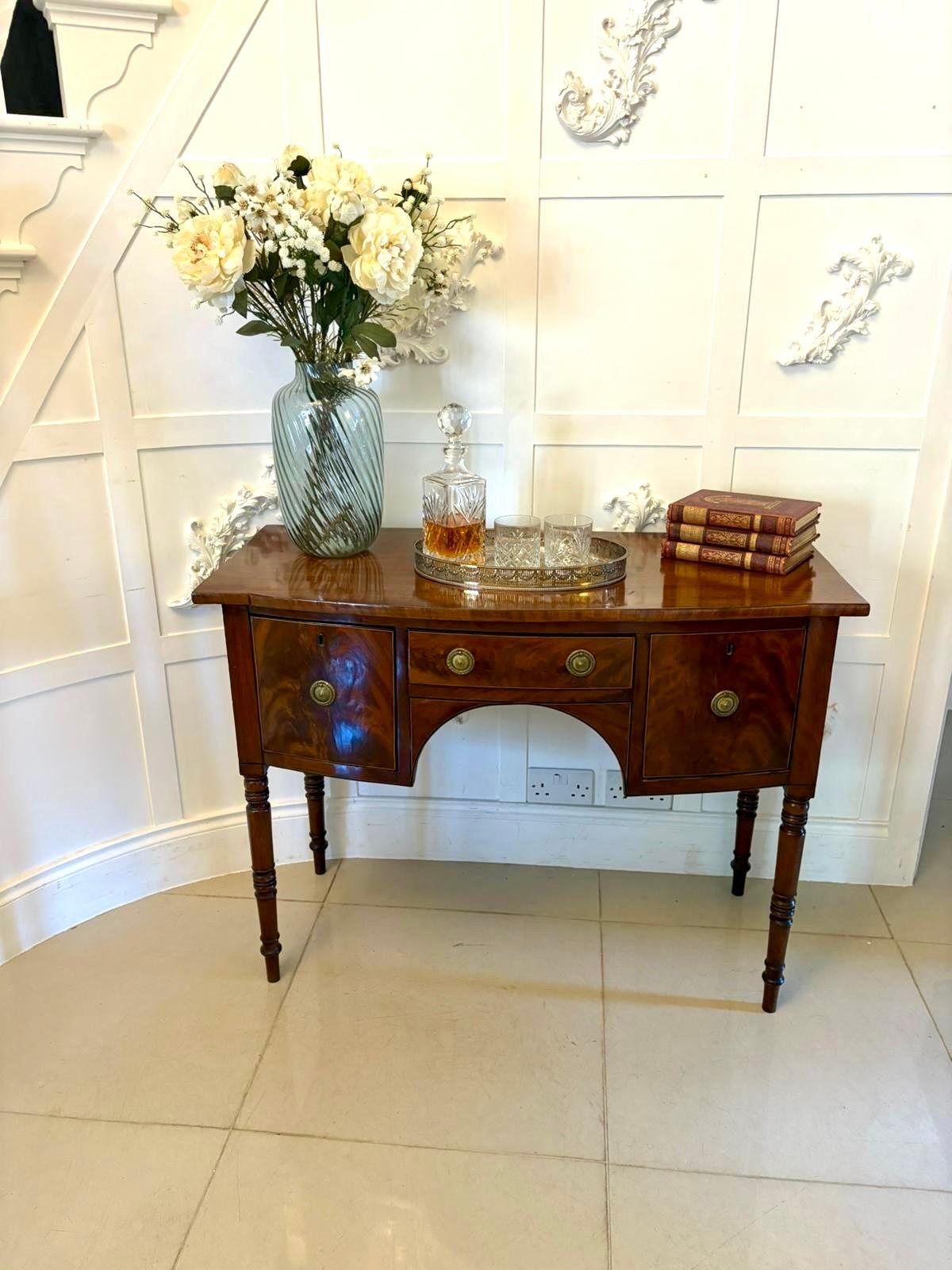 Small antique George III quality figured mahogany bow front sideboard having a quality figured mahogany bow front top above 3 bow fronted oak lined drawers with inlaid satinwood stringing and brass handles standing on 4 elegant turned tapering