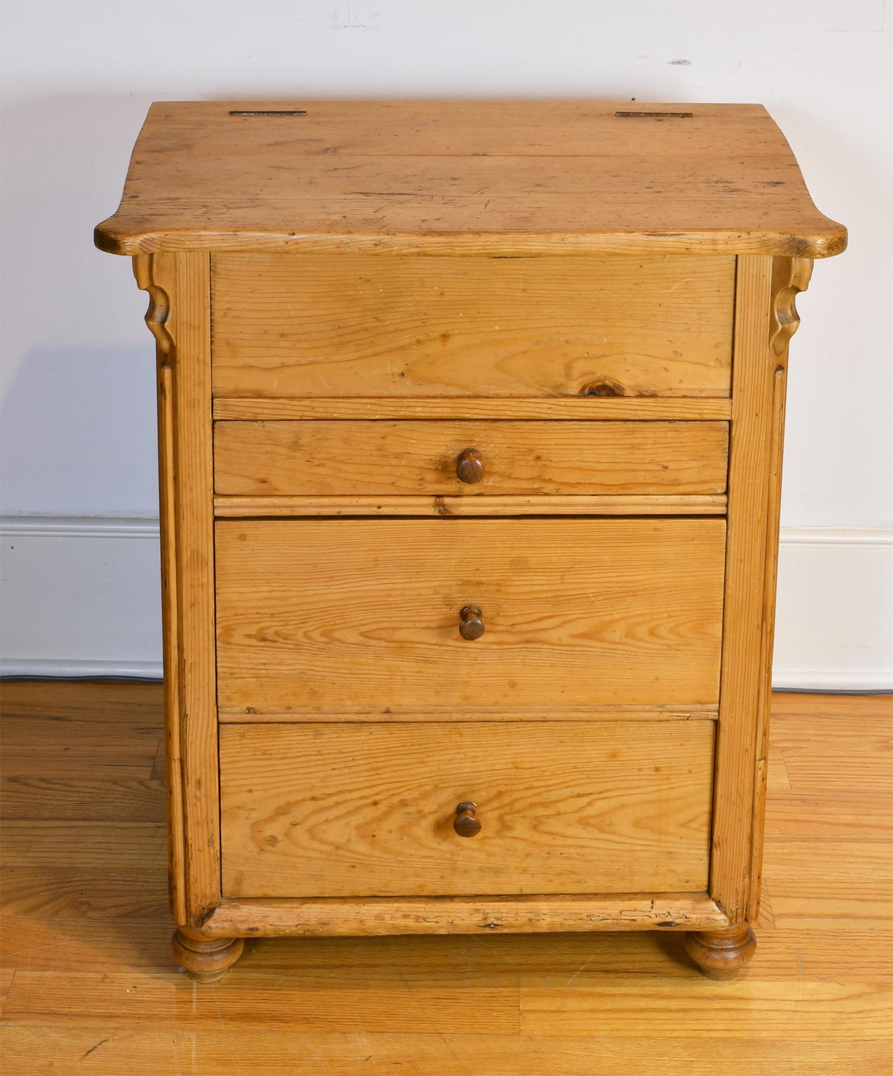 An unusually small antique Louis Philippe chest in light honey-colored pine with three drawers in staggered heights, with original turned wooden knobs, and resting on four turned feet. Top lifts to a storage compartment that would have held a