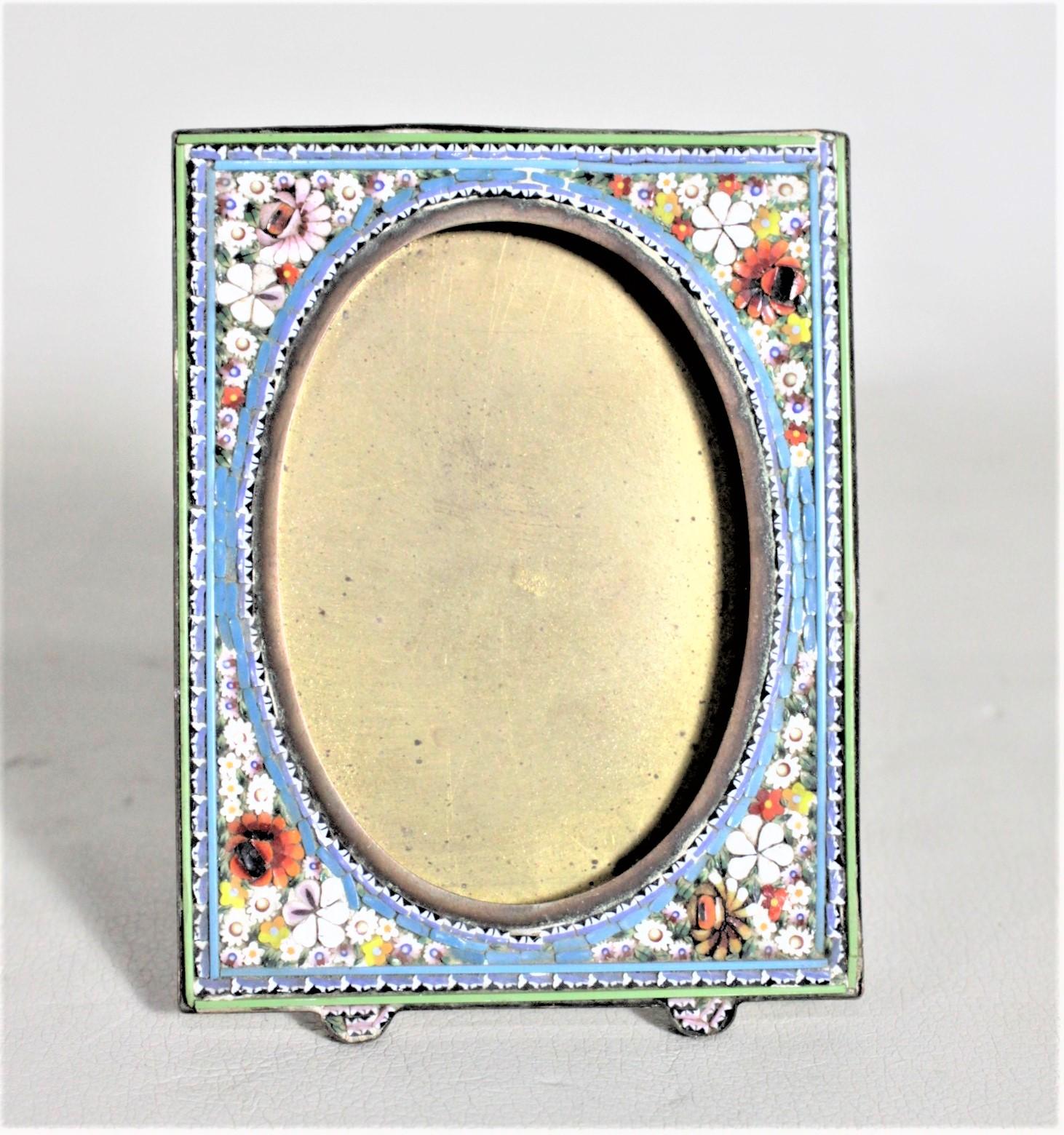 This small art glass and brass picture frame is unsigned, but presumed to have been made in Italy in approximately 1920. The front of the frame is done with a series of glass canes with a vibrant green border and turquoise blue background with a