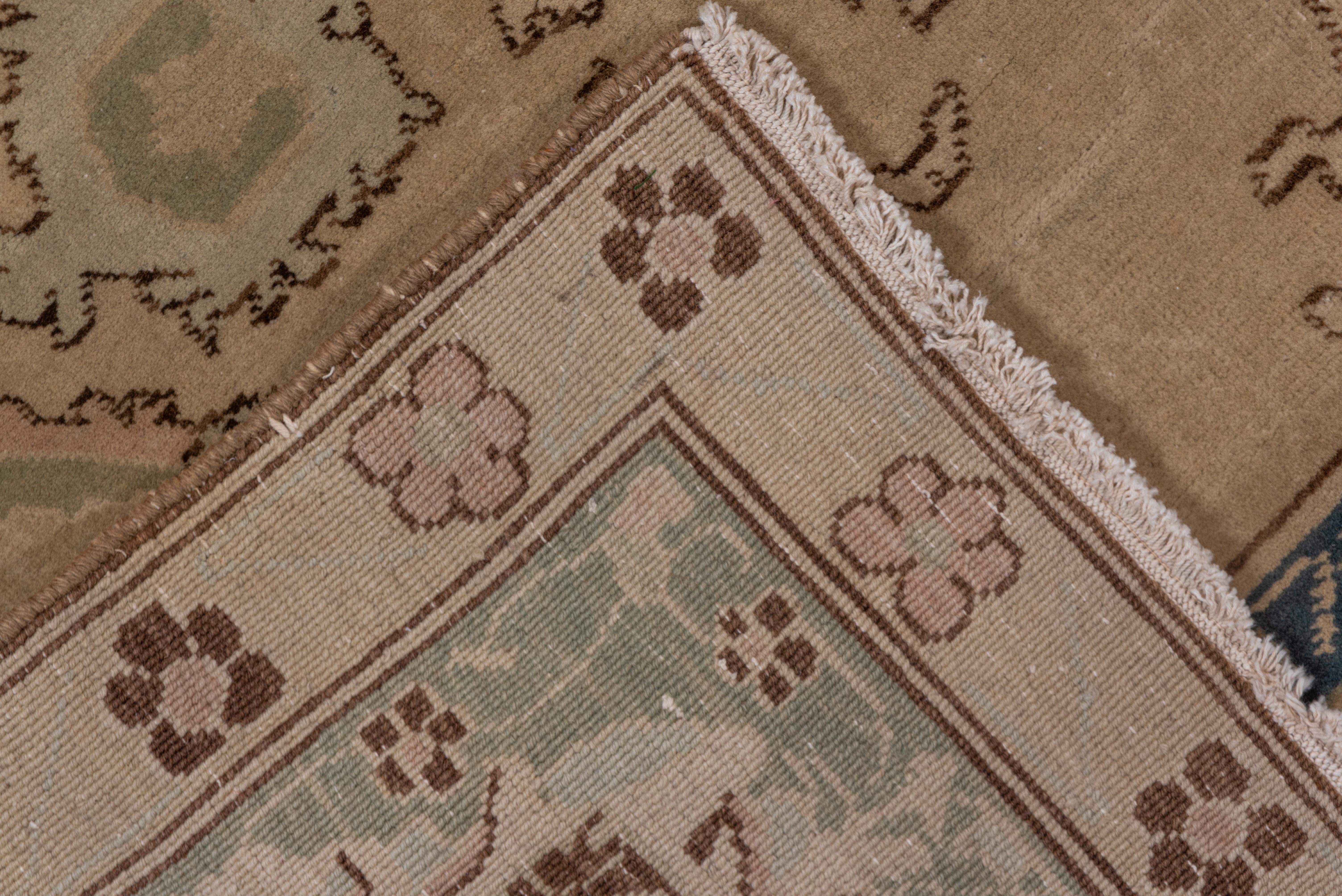 The warm ivory field of this northern Indian city small carpet shows an unusual all-over repeating pattern of dark brown outlined palmettes derived distantly from the ubiquitous 